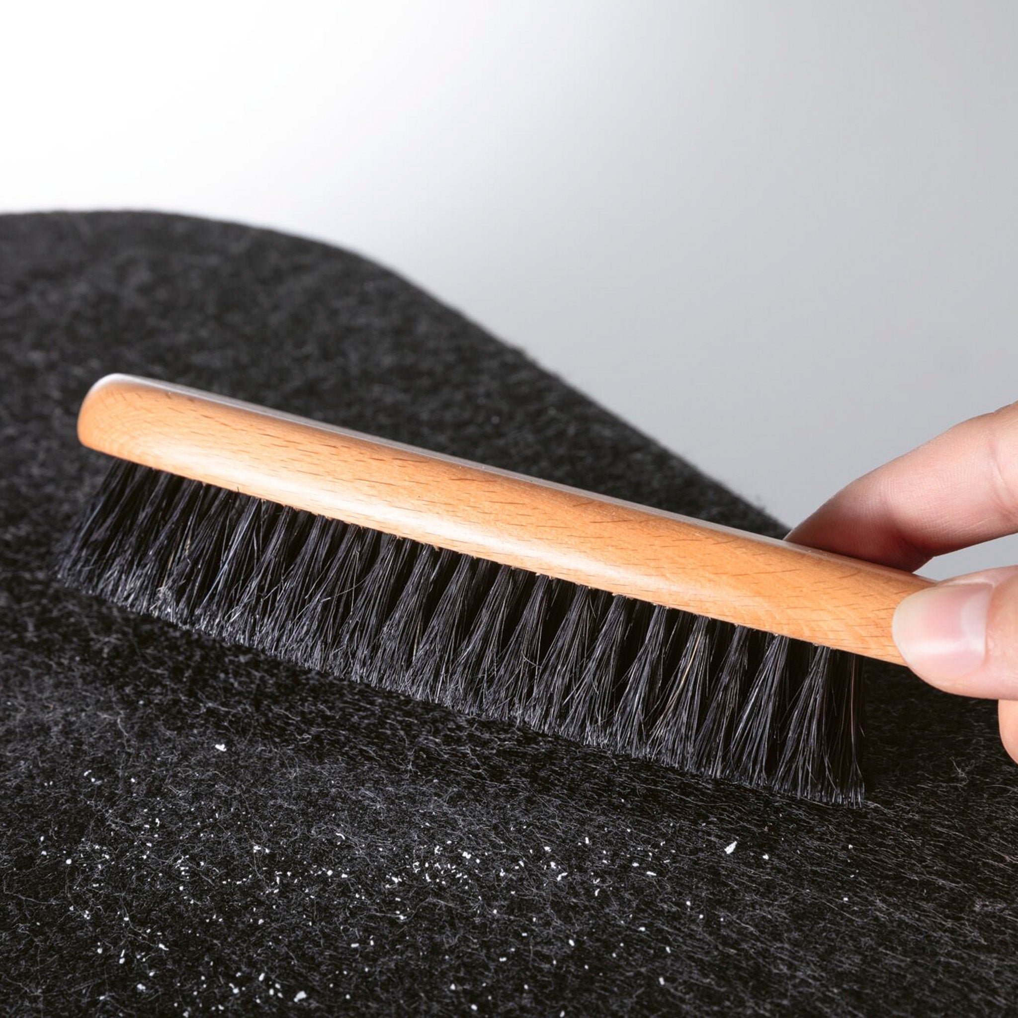 Using a wooden clothes brush to remove lint from the luxurious fabric of the Paulmann - Tulga 15W LED Oval Wall Light with 3-Step Dim in Anthracite.