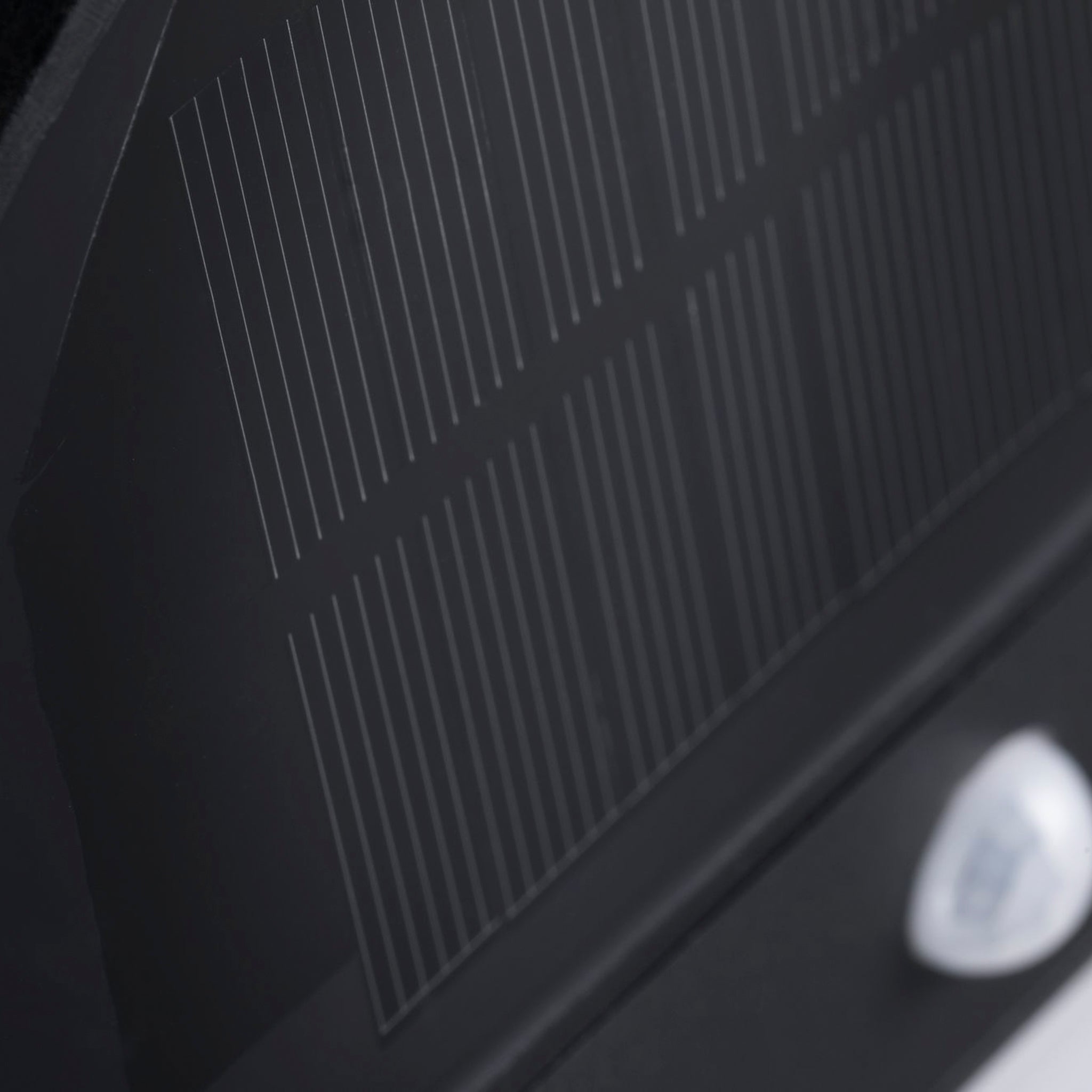 Close-up of a dark solar panel on the Paulmann Outdoor Elios 1W LED Solar Wall Light with Motion Detection in Anthracite, showcasing advanced solar technology, with visible grid lines and a small, blurred white object in the lower right corner.