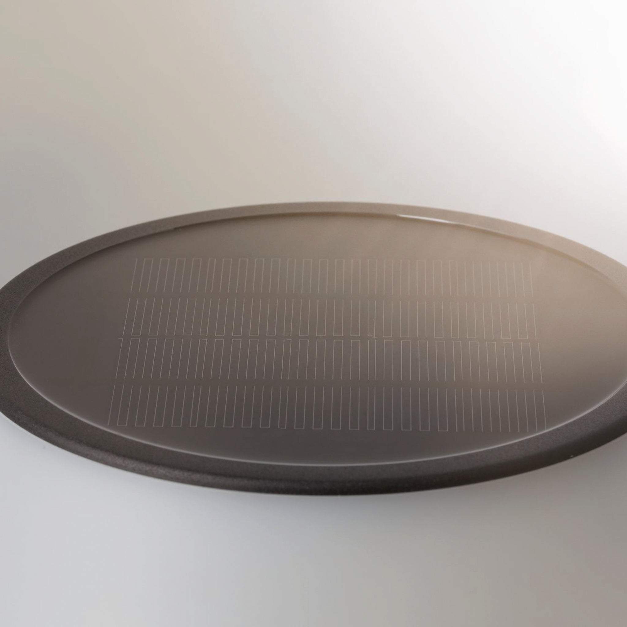 Black oval solar panel on a white surface with light reflections, perfect for the Paulmann Outdoor Lillesol 0.8W LED Solar Table Lamp with 3-Step Dim in Stainless Steel.