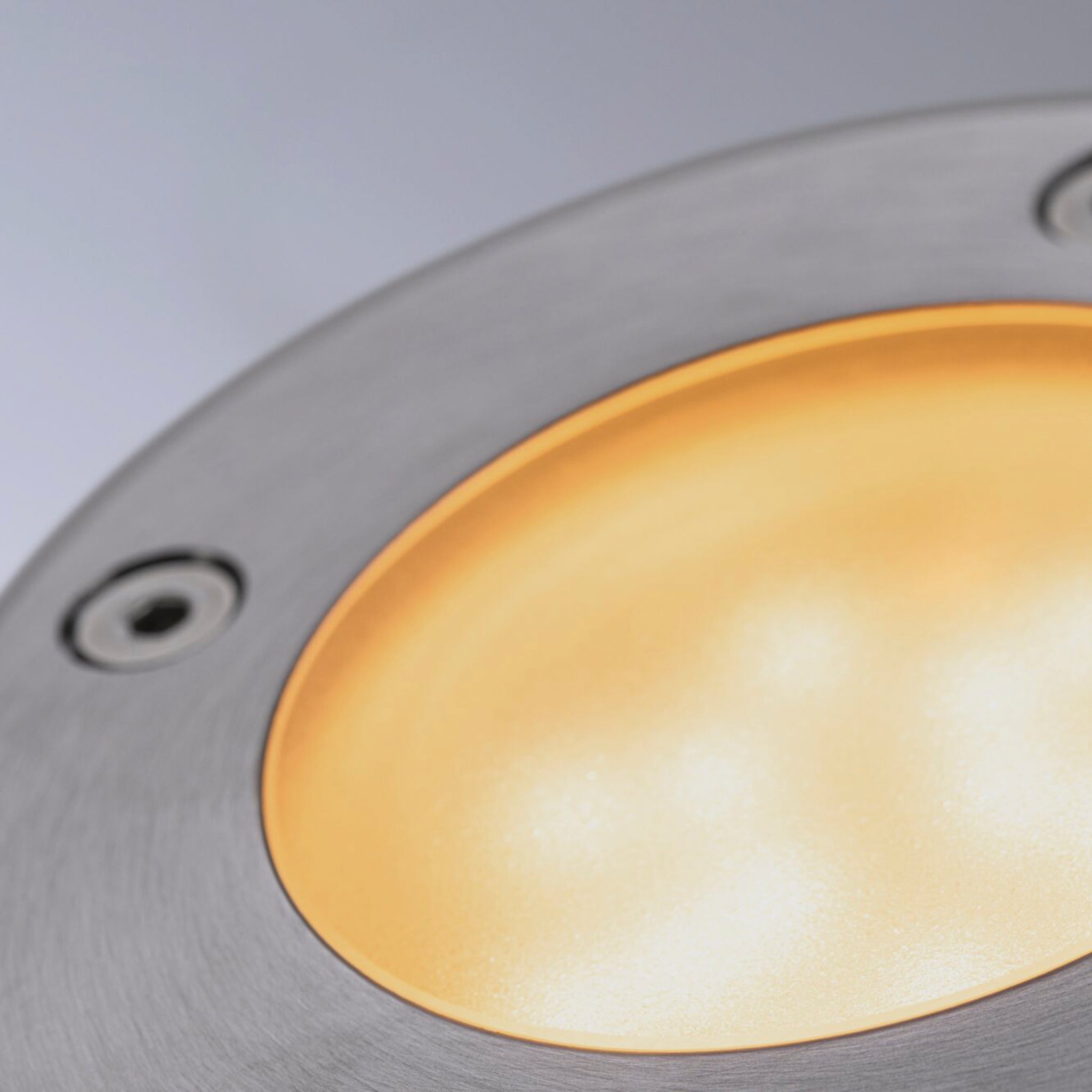 Close-up of the Paulmann Plug & Shine Outdoor 5.2W LED Recessed Spotlight in black, featuring a warm yellow glow and metallic rim, compatible with Zigbee 3.0 for seamless integration with smart systems.