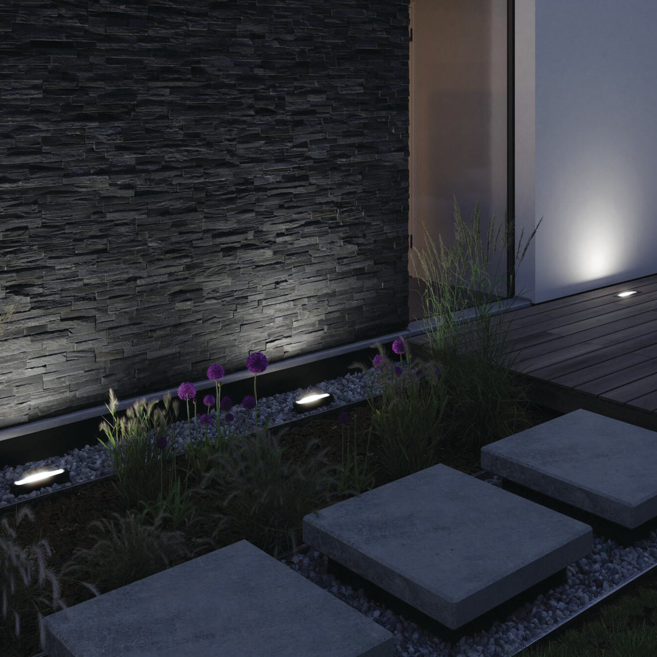 A contemporary outdoor space with a stone path, slate wall, and ambient night lighting is enhanced by the Paulmann Outdoor Ito 6W LED Wall Washer Light in Anthracite, which features IP67 protection for all-weather durability.
