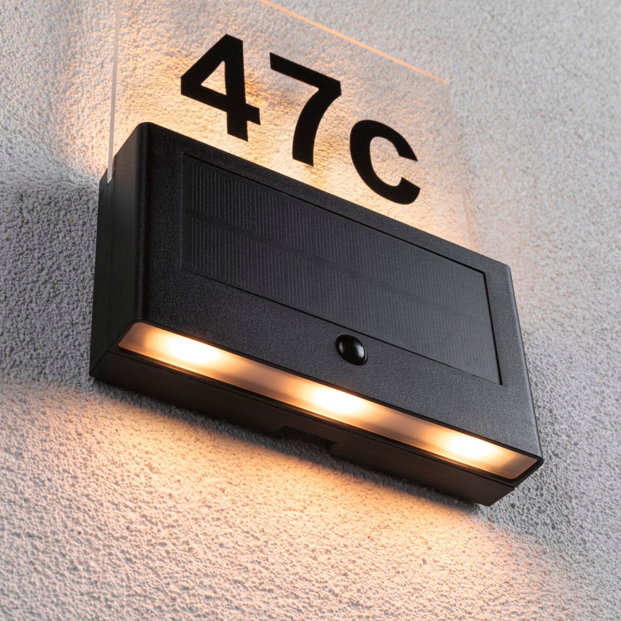 The Paulmann Outdoor Neda Solar House Number 1W LED in Anthracite enhances the textured wall with a gentle glow through its insect-friendly design and dusk sensor for automatic illumination.