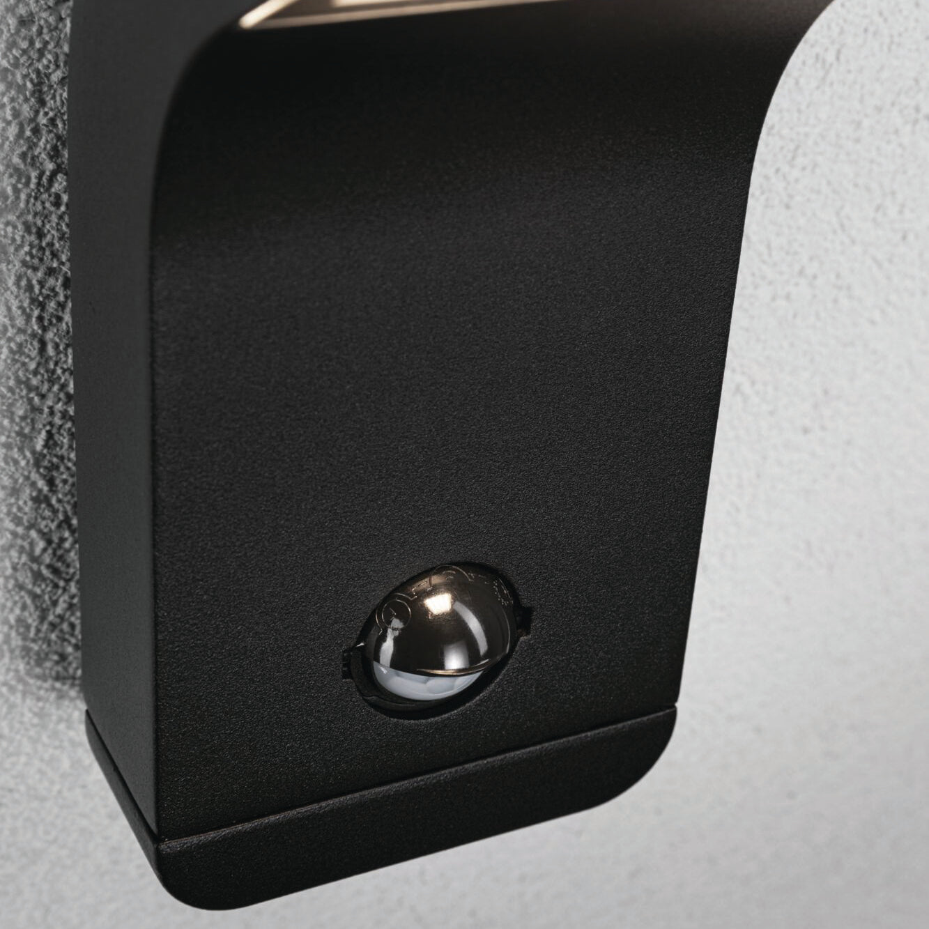 Close-up of a corrosion-resistant black motion sensor mounted on a gray wall, enhancing the sleek design of the Paulmann Outdoor Kulma 9W LED Wall Light with Motion Detection in Anthracite nearby.