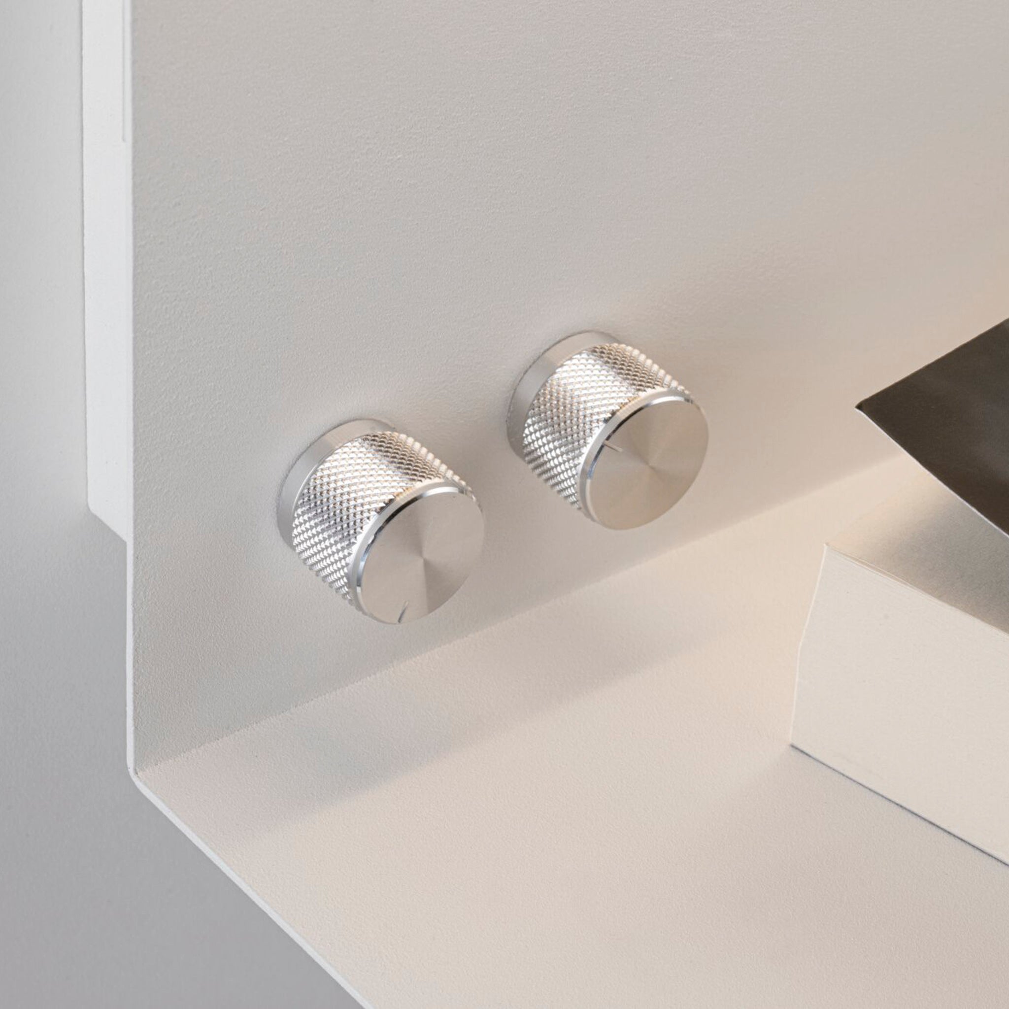 Two round knobs with a textured grip on the matt white surface of the Paulmann - Jarina 7.5W LED Dimmable Wall Light with USB Port, casting soft shadows.