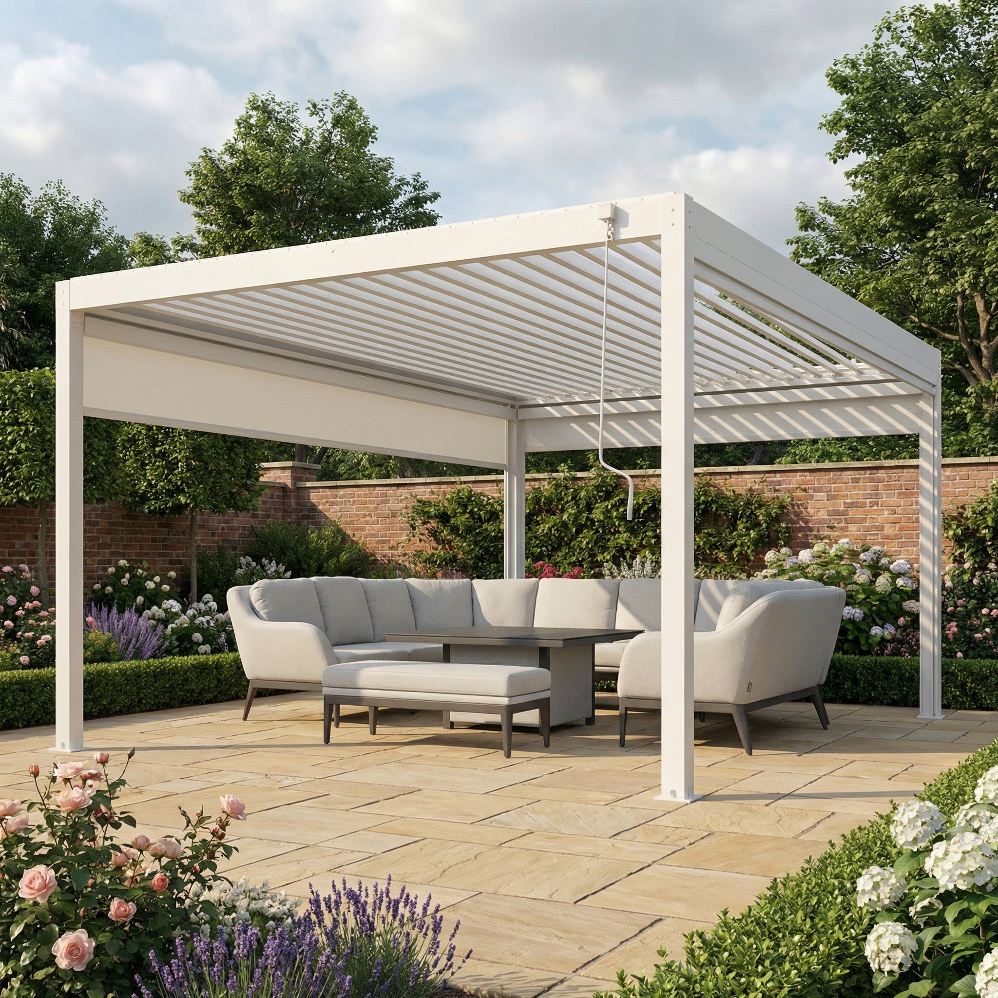 The PergoSTET Plus 4m x 4m Square Pergola in white, with 3 manual side blinds and LED lighting, stands over an outdoor seating area in a landscaped garden blooming with flowers.