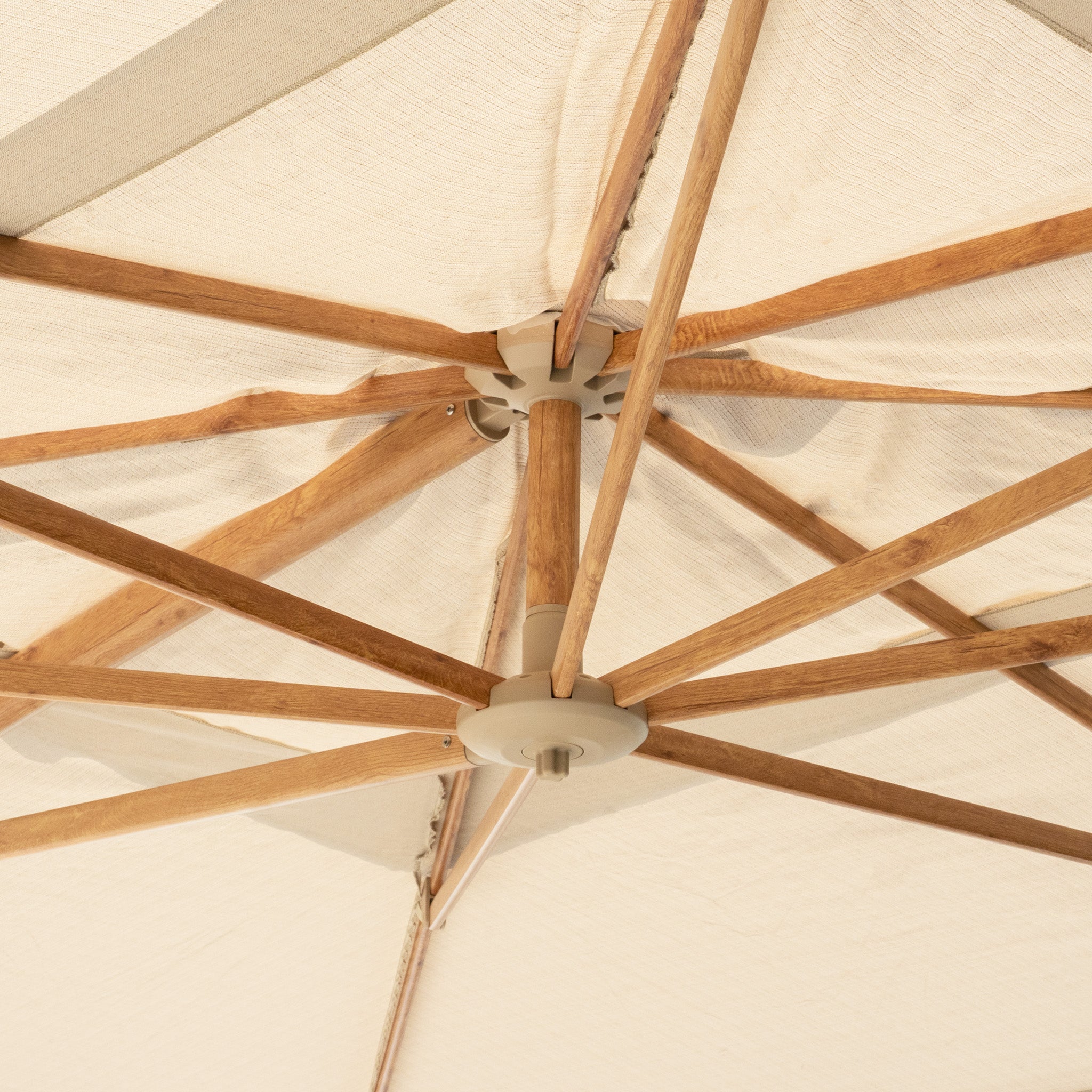 A close-up view from underneath the wooden frame and fabric of a Finca 4m x 3m Cantilever Parasol in Sand, ideal for sun protection and elevating your outdoor living space.
