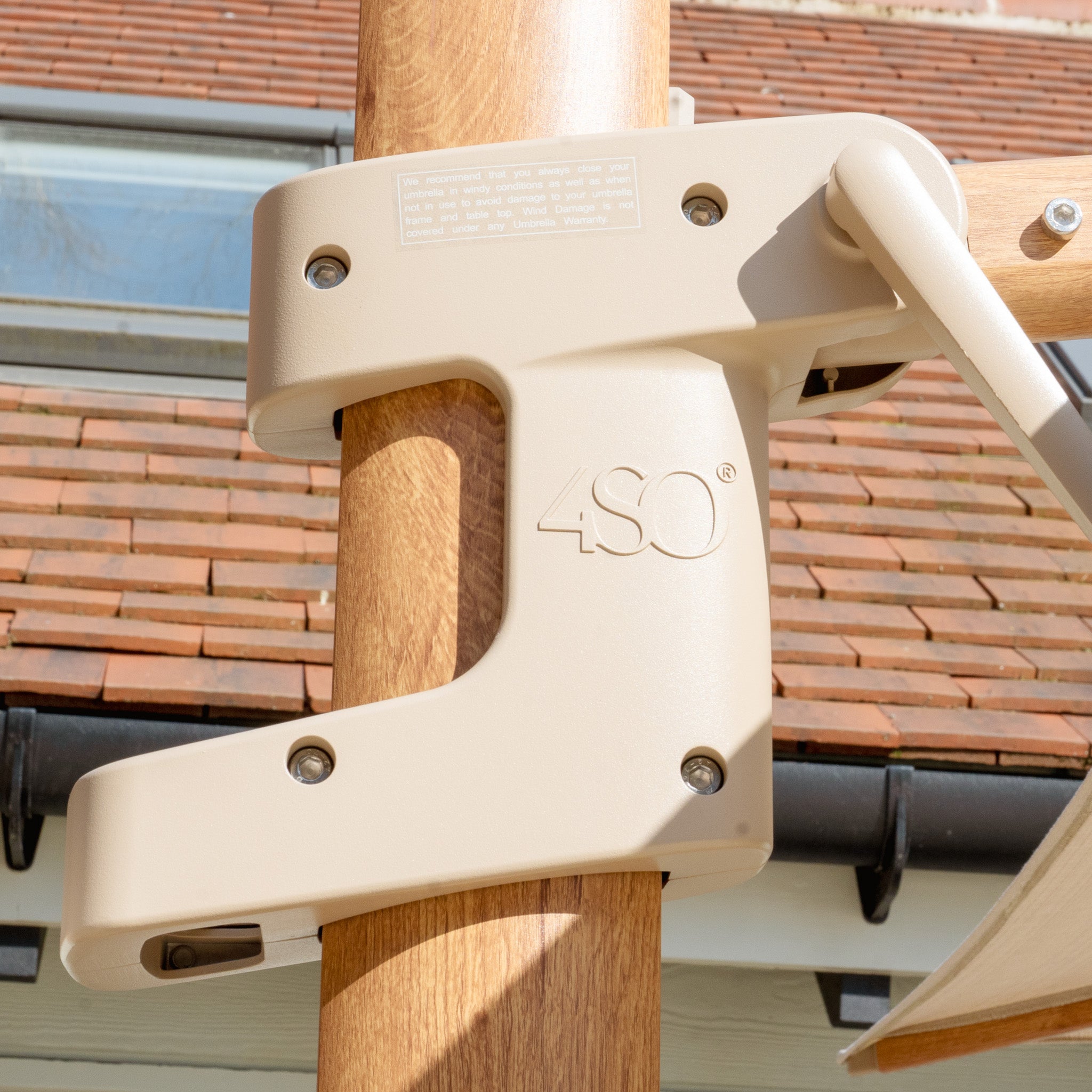 Close-up of a sand bracket labeled "4SO" from the Finca 4m x 3m Cantilever Parasol, attached to a wooden pole. This setup, perfect for outdoor living and sun protection, is set against a tiled roof backdrop.