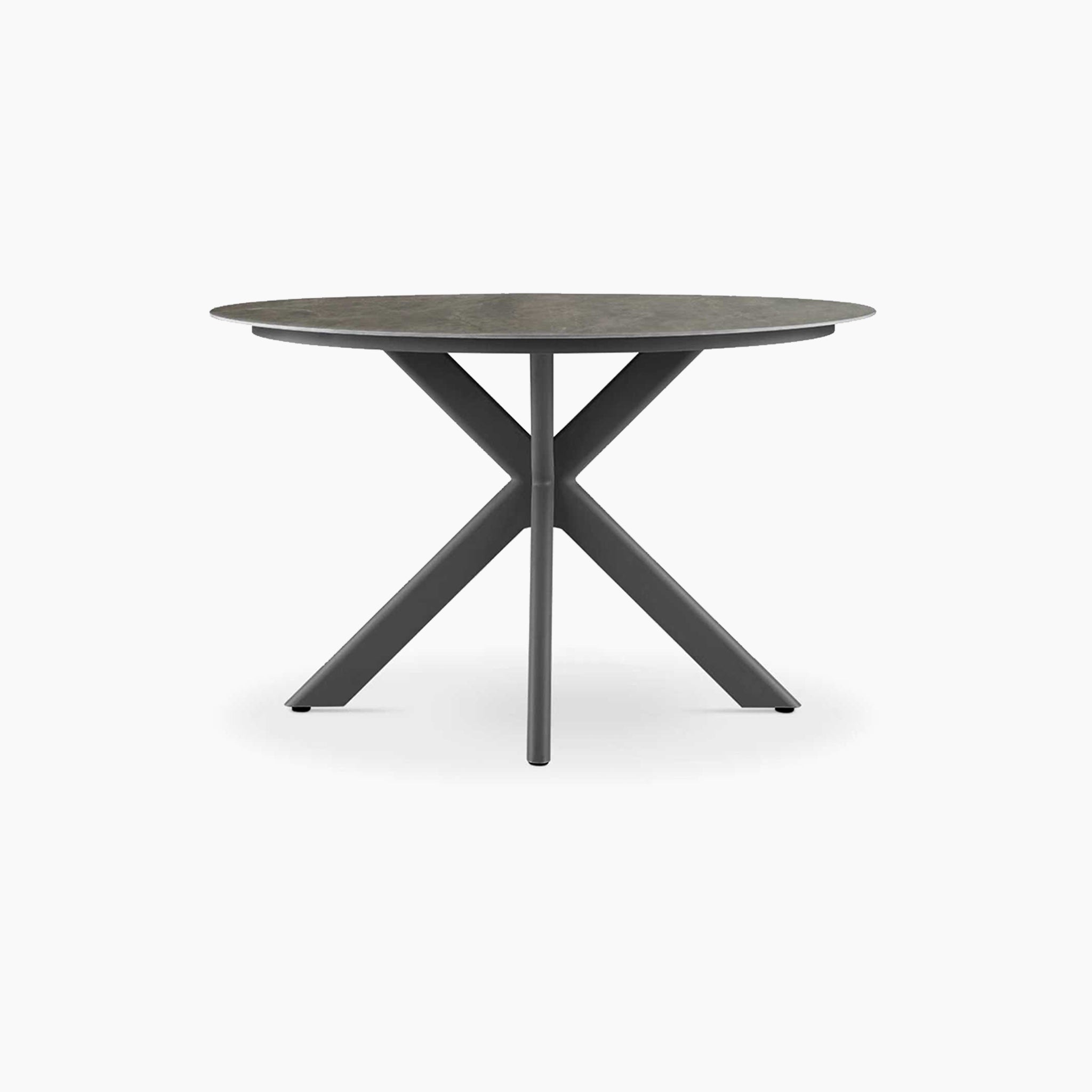 The Albatross 4 Seat Round Dining Table in Charcoal features a modern sintered stone top and three intersecting angled legs. This weather-resistant table offers stylish durability for any outdoor setting.