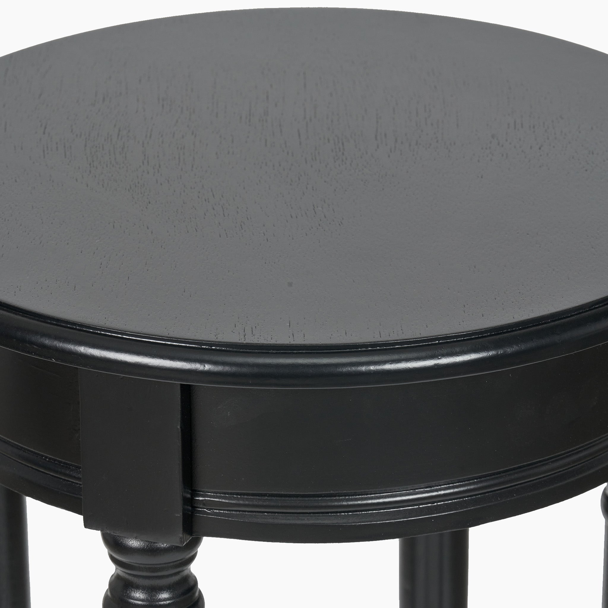 Close-up of a round, black pine wood accent table from the Heritage Collection, featuring decorative legs and crafted by Pacific Lifestyle.