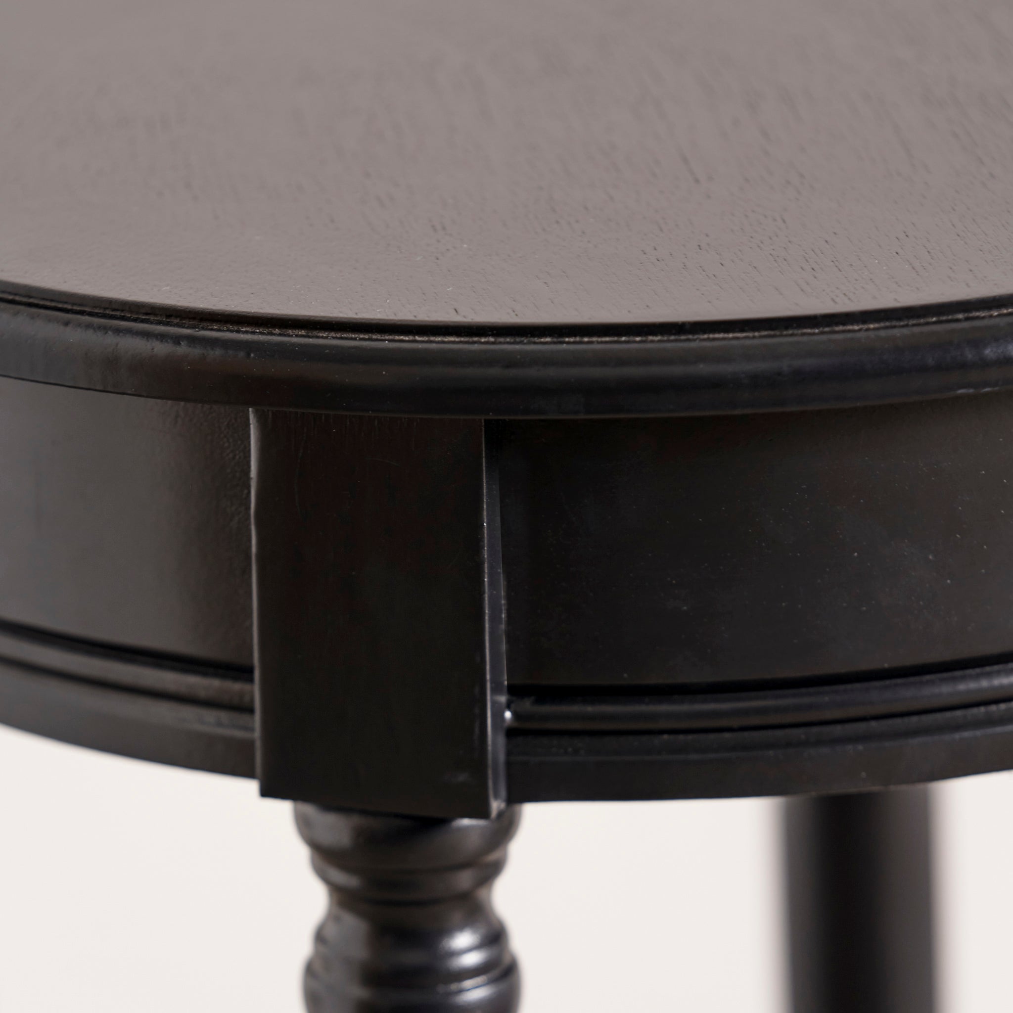 Close-up of the round edge and textured surface of the Pacific Lifestyle - Heritage Black Pine Wood Round Accent Table.
