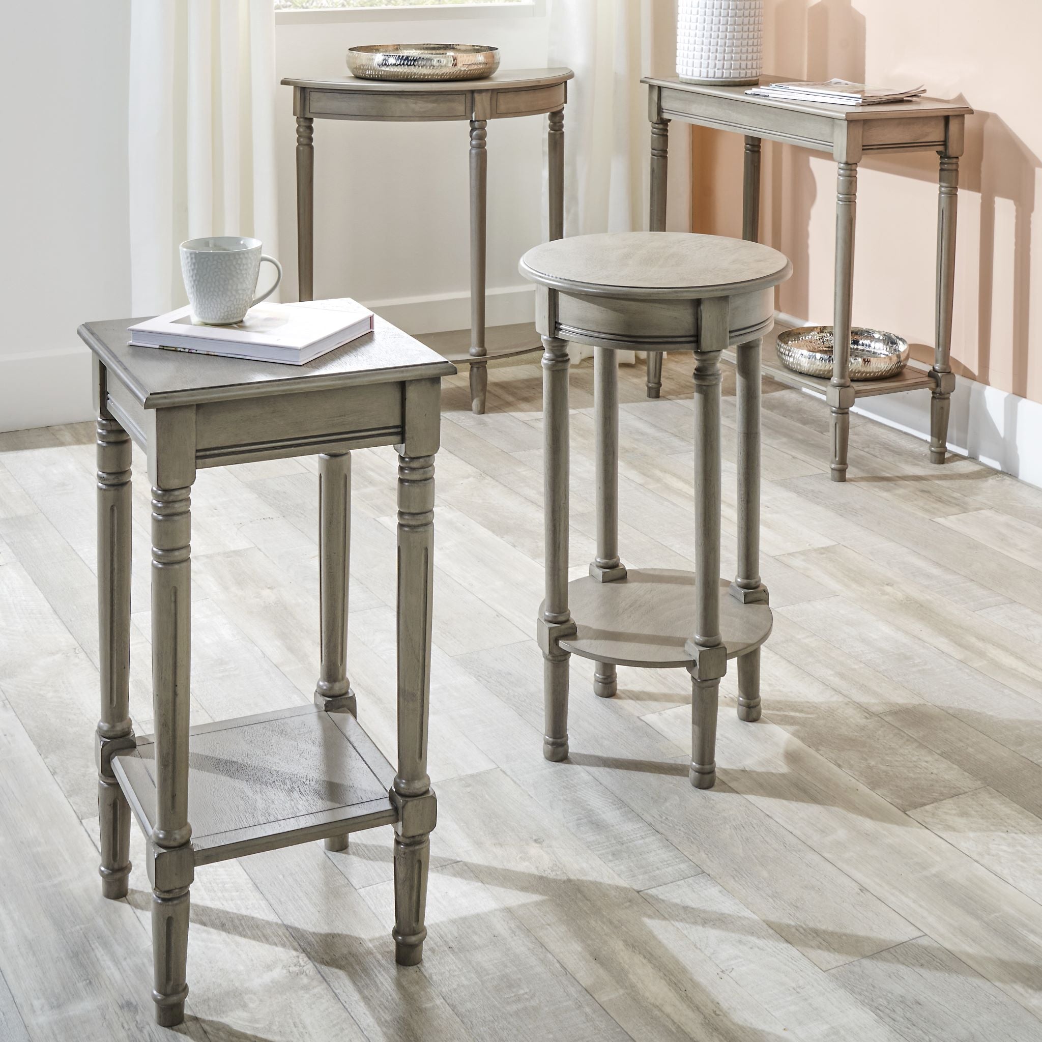 A room from the Ashwell Collection showcases a Pacific Lifestyle - Heritage Taupe Pine Wood Square Accent Table with a teacup, books, and decorative trays on a wooden floor.
