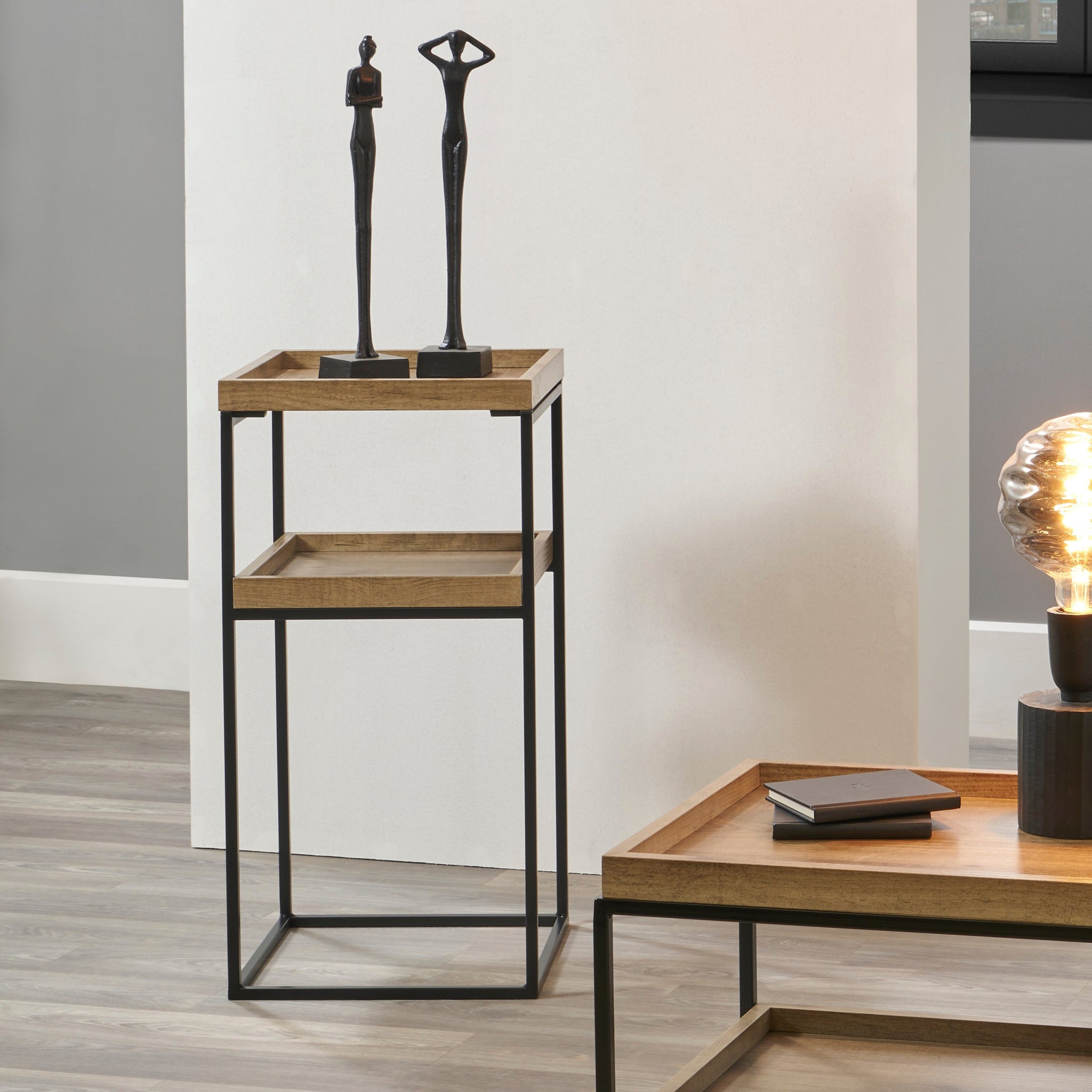 The Pacific Lifestyle Gallery Natural Wood Veneer and Black Metal Side Table offers a contemporary vibe with its wooden tray and slim black metal frame, perfect for displaying sculptures or a lamp.