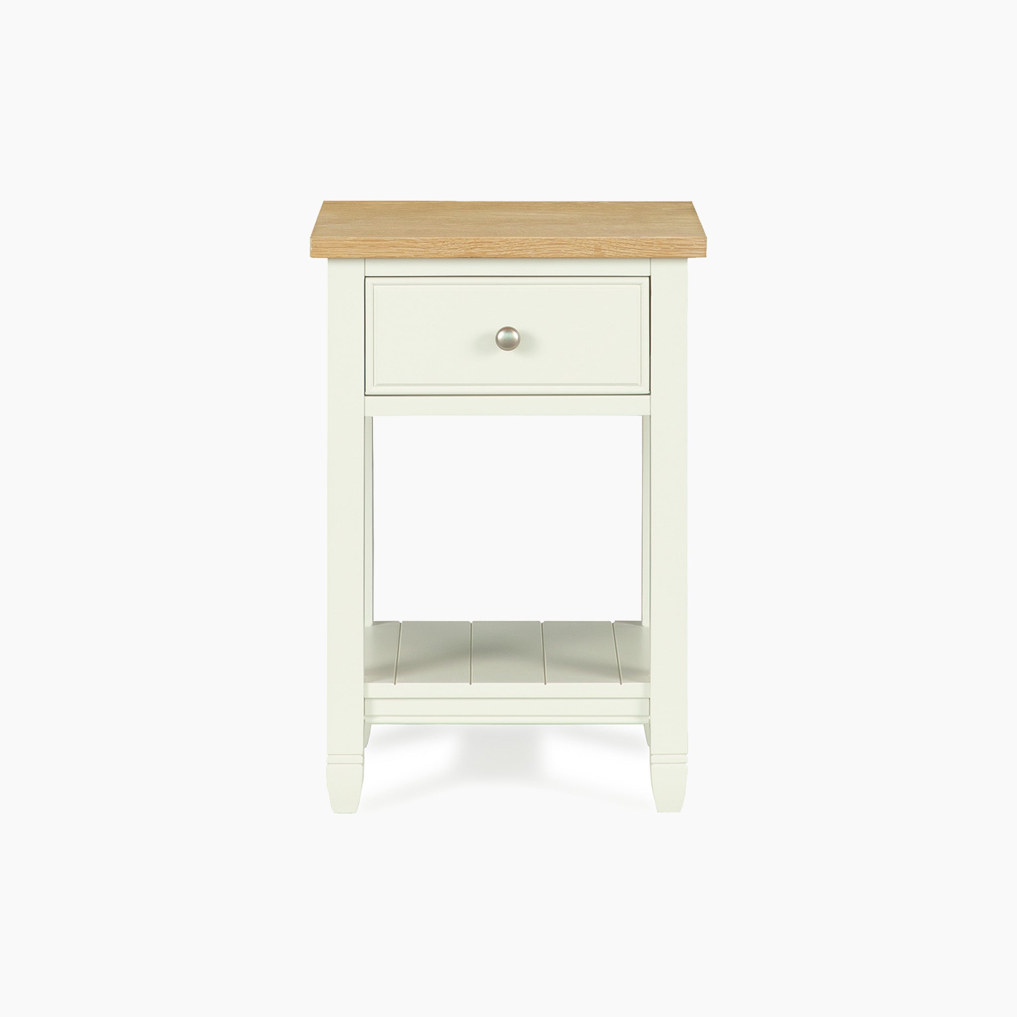 The Amberley Bedside Table in Warm White features a single drawer, lower shelf, and a light wood top—perfect for modern country interiors. Its front-facing design highlights its charm as an ideal bedside table.
