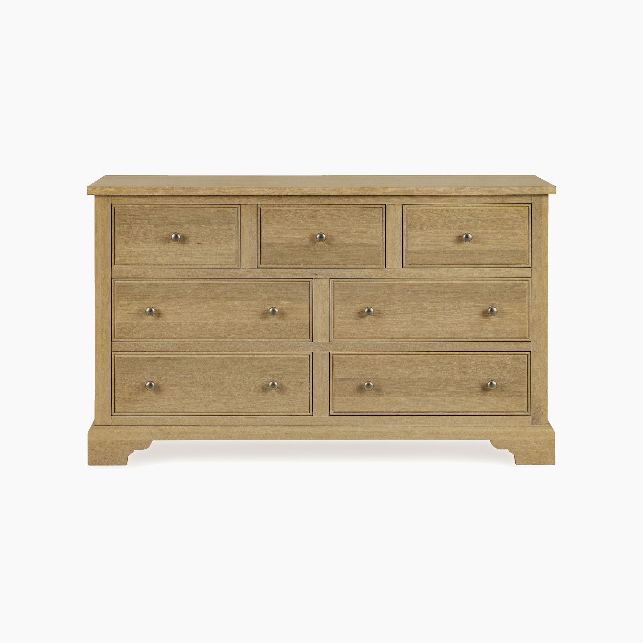 The Amberley 3 Over 4 Chest of Drawers in Light Oak features seven spacious drawers with round metal knobs, offering elegant and practical bedroom storage. This solid oak piece adds a stylish touch set against a white background.