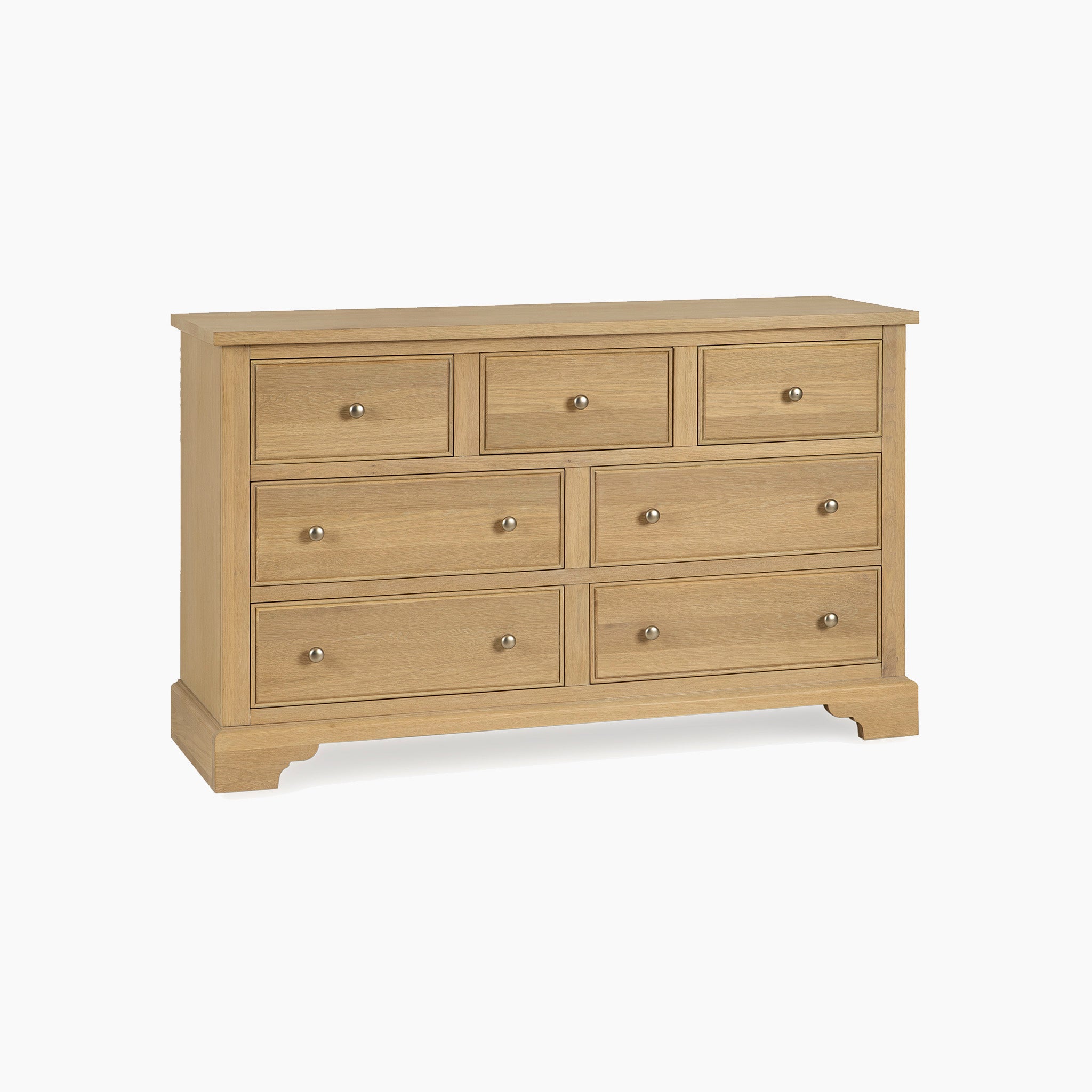 The Amberley 3 Over 4 Chest of Drawers in Light Oak features seven spacious drawers with round metal knobs, providing stylish storage for your bedroom.