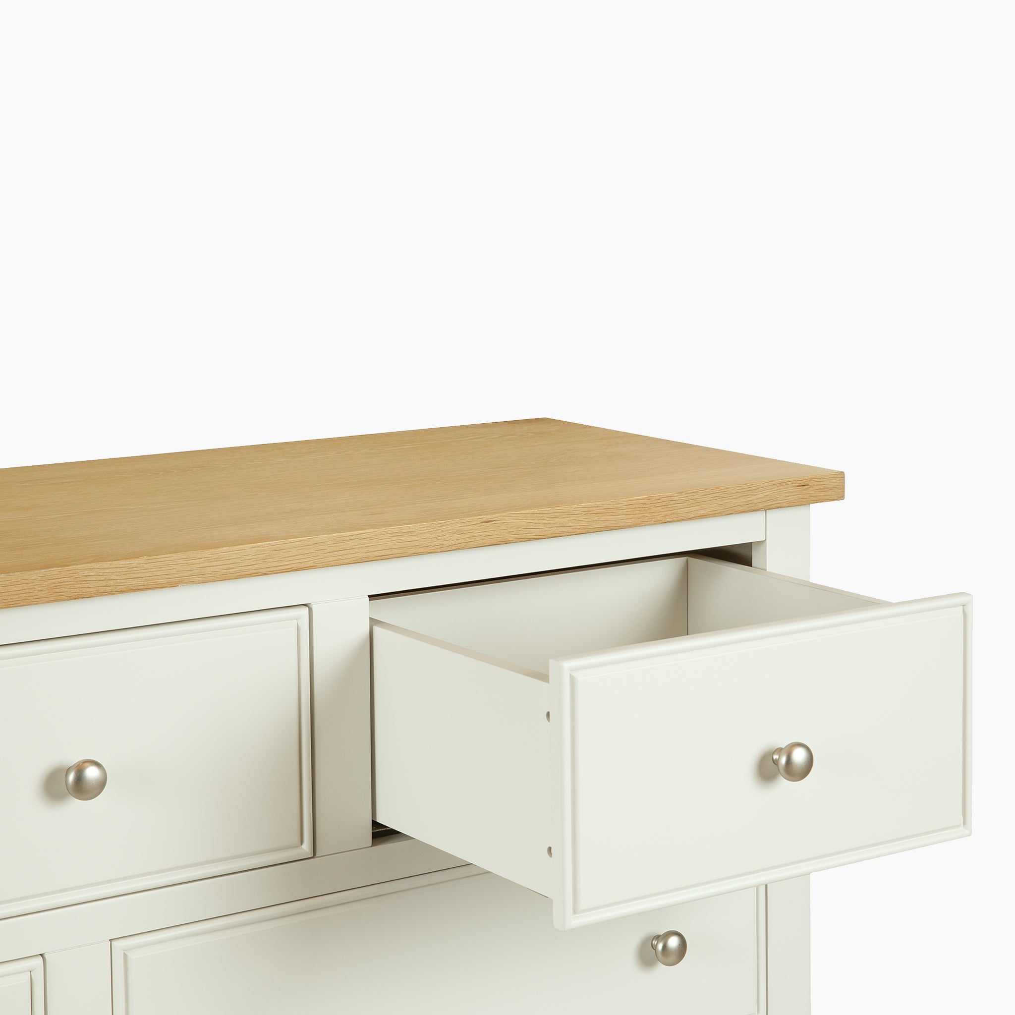 The Amberley 3 Over 4 Chest of Drawers in Warm White features an oak top and silver knobs, with one drawer partially open against a plain background.