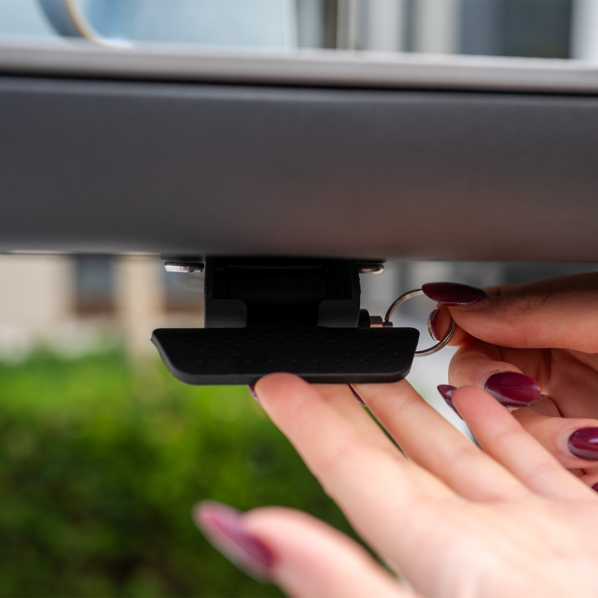 Close-up of a person unlocking a car roof box latch with a key, greenery blurred in the background—ideal before setting up your Alva Corner Dining Set with Rising Table and Armchair in Grey (Right Hand) for an outdoor gathering.