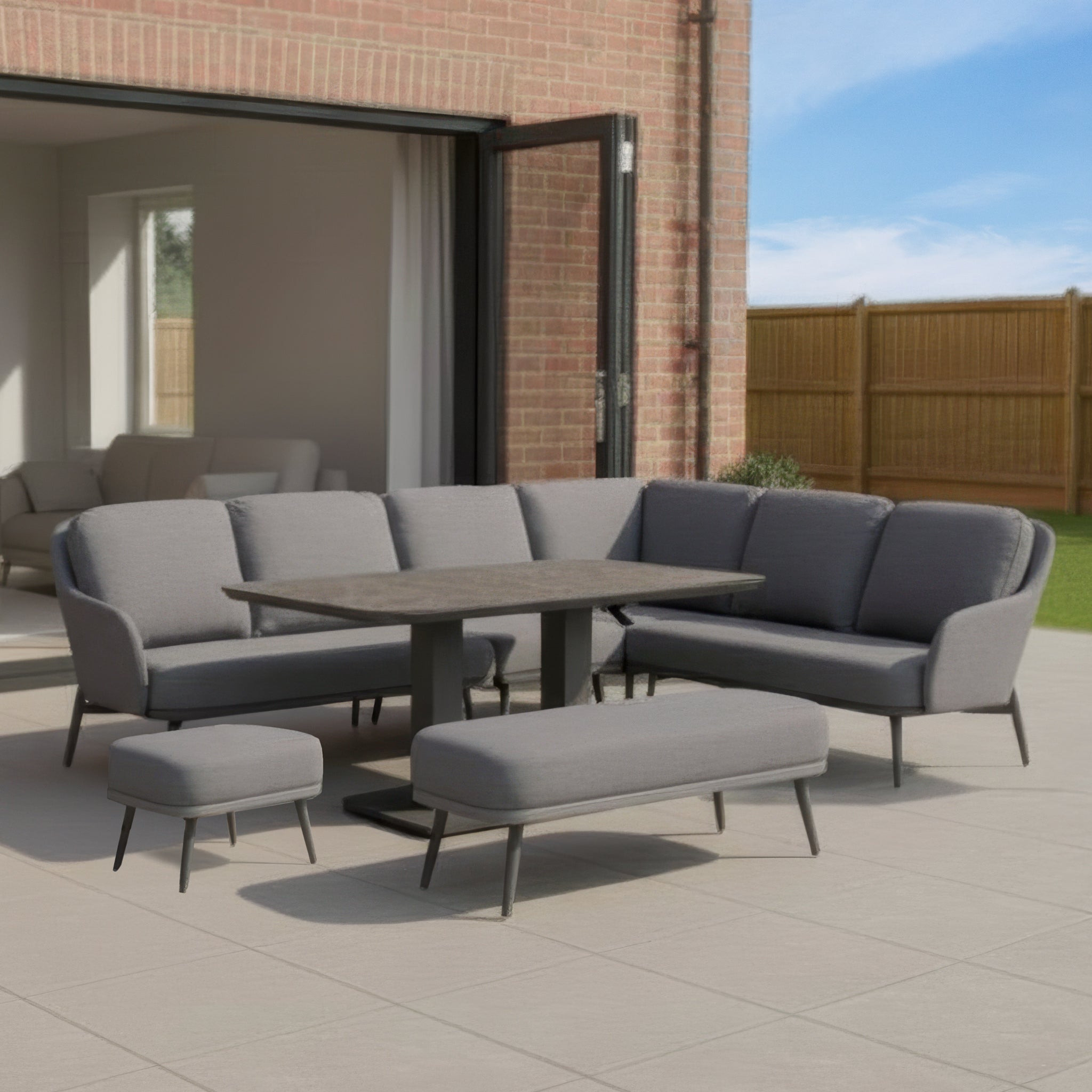The Alva Corner Dining Set with Rising Table in Grey features modern garden furniture—a stylish bench and table—perfect for outdoor comfort on your patio or yard.