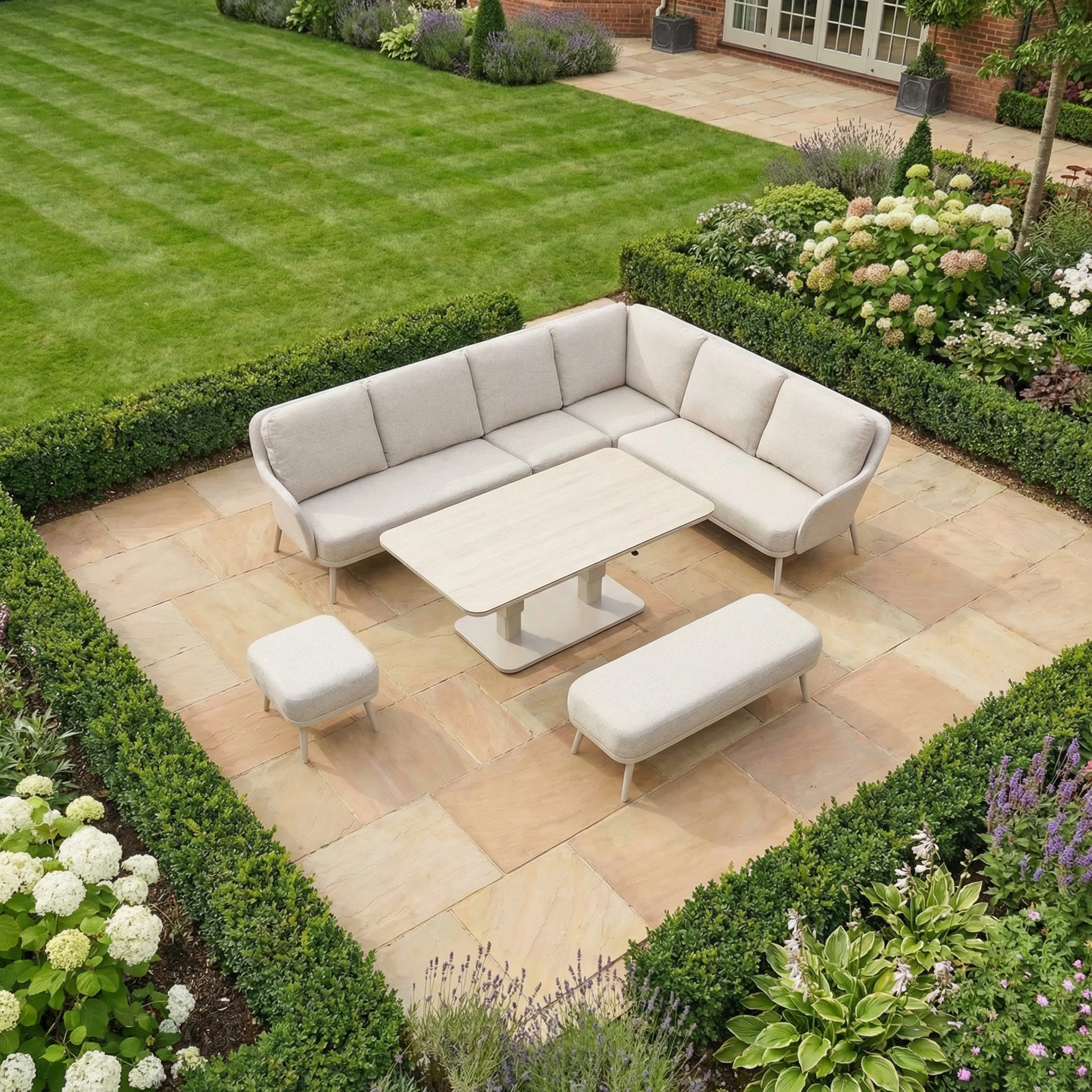 Modern patio with the Alva Corner Dining Set with Rising Table in Fawn (Right Hand)—a beige sectional sofa and benches surrounded by lush greenery—ideal garden furniture for relaxing or entertaining.