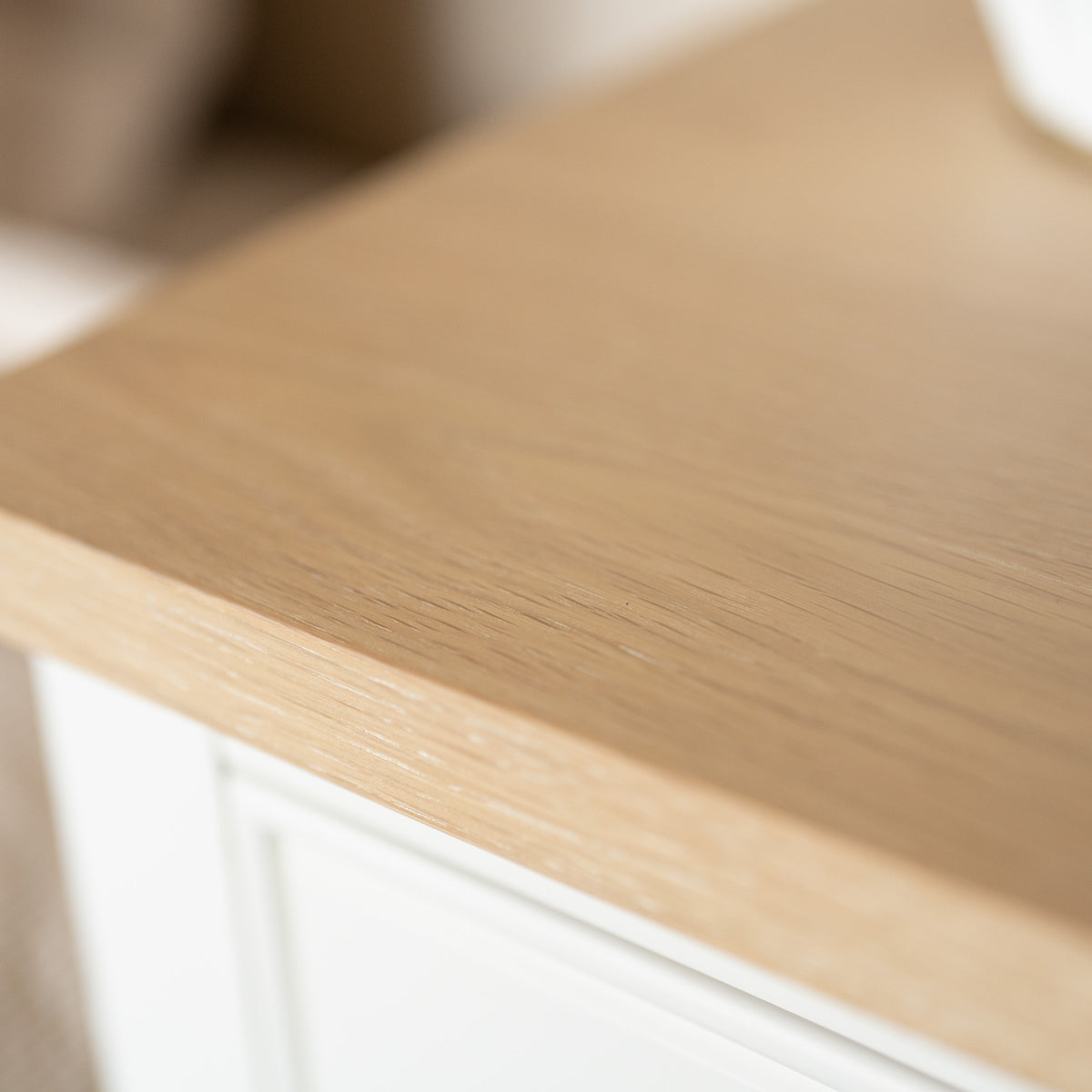 Close-up of a light wood tabletop with a smooth finish and soft lighting, capturing the timeless appeal of modern country furniture—perfect for the Amberley Bedside Table in Warm White or any elegant bedside table.