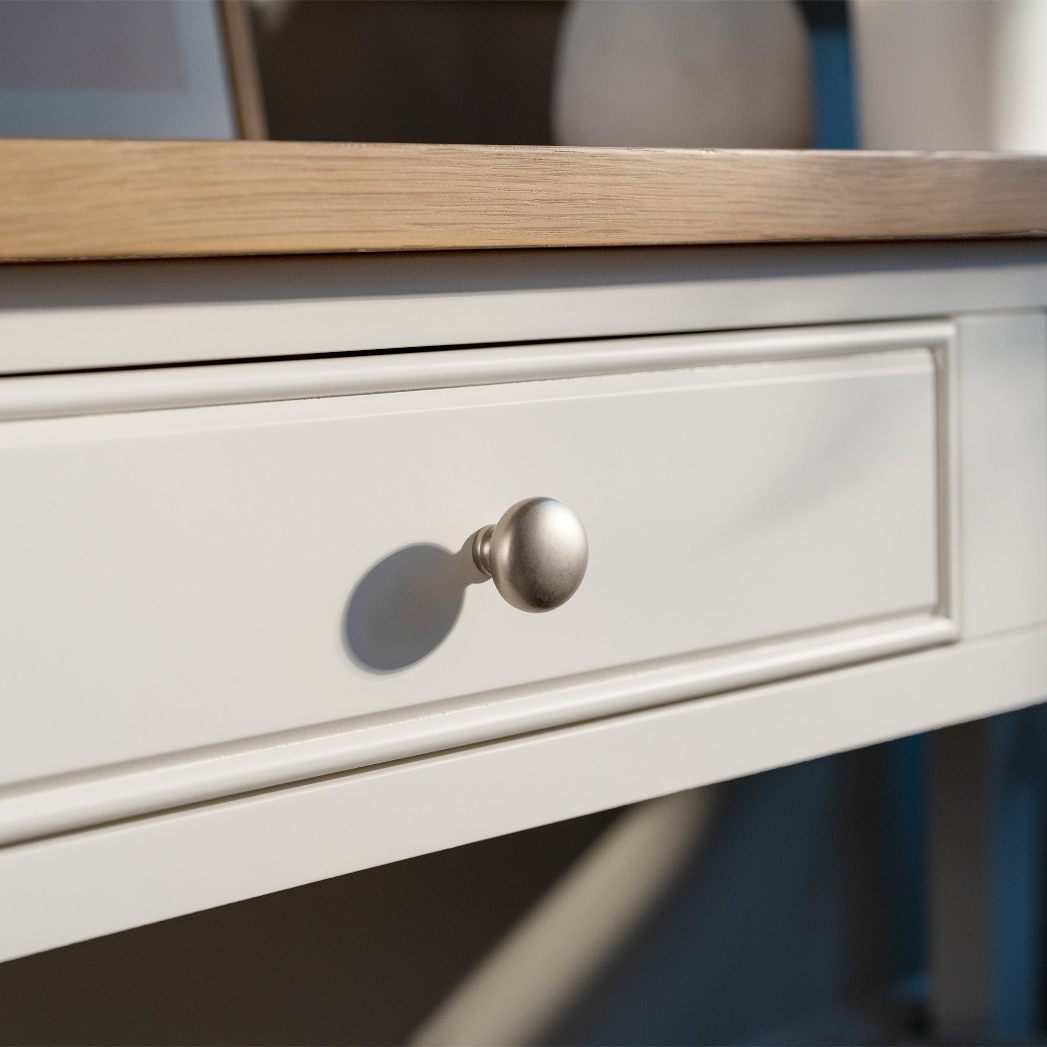 Close-up of the Amberley 2 Drawers Console Table in Warm White, featuring a farmhouse-style drawer with a round silver knob and an oak wood tabletop above.