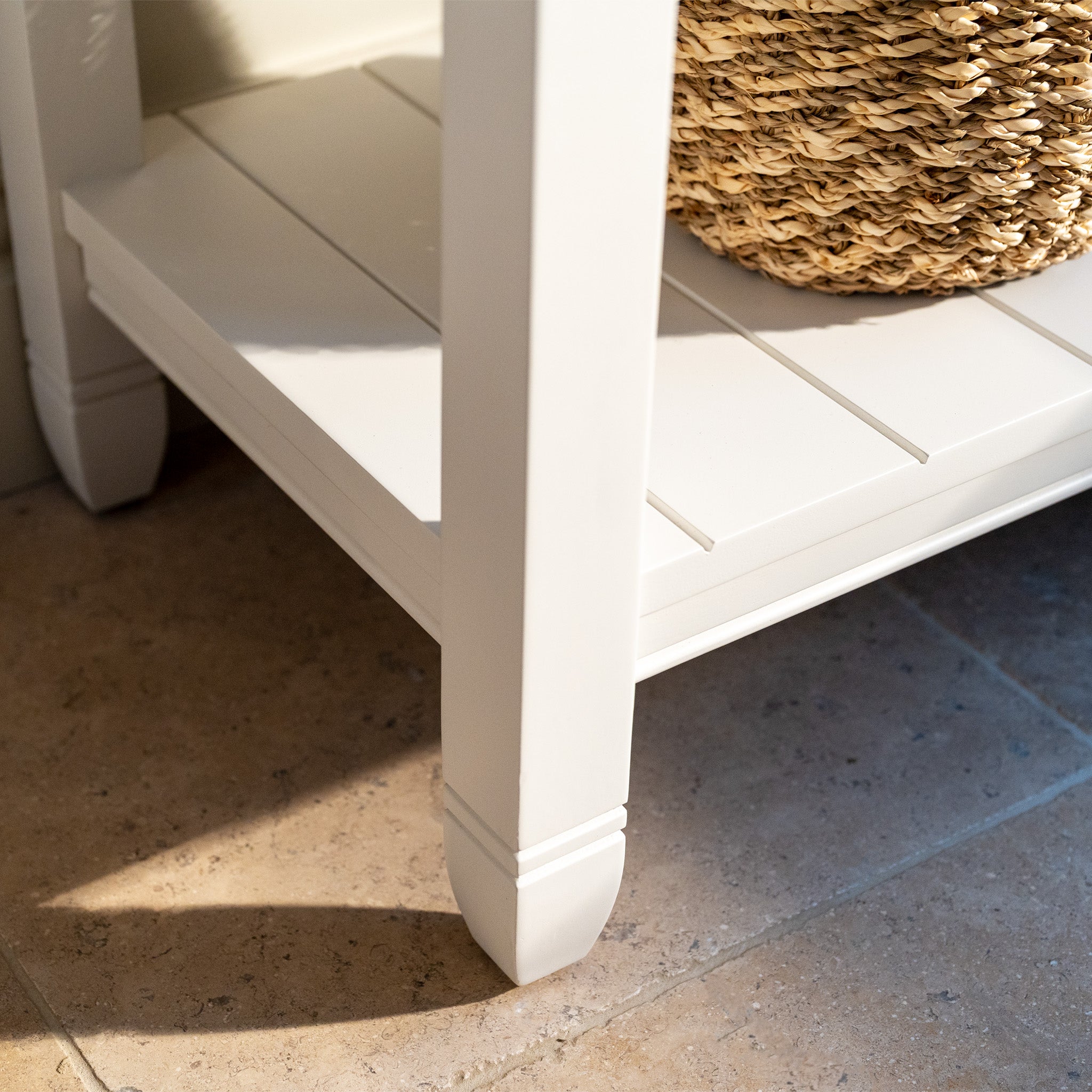 An Amberley 2 Drawers Console Table in Warm White with an oak top stands on a tiled floor, featuring a woven basket placed on its lower shelf.