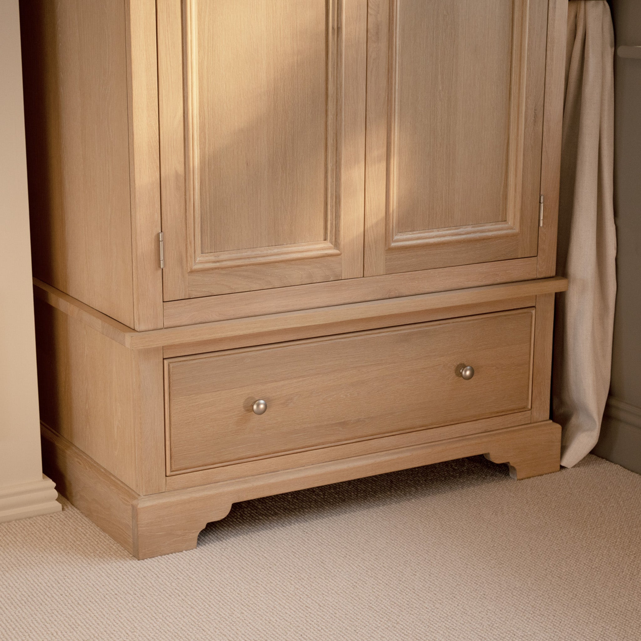 The Amberley Double Wardrobe in Light Oak features two doors, a spacious lower drawer, and a solid oak build, making it a stylish addition to any bedroom.