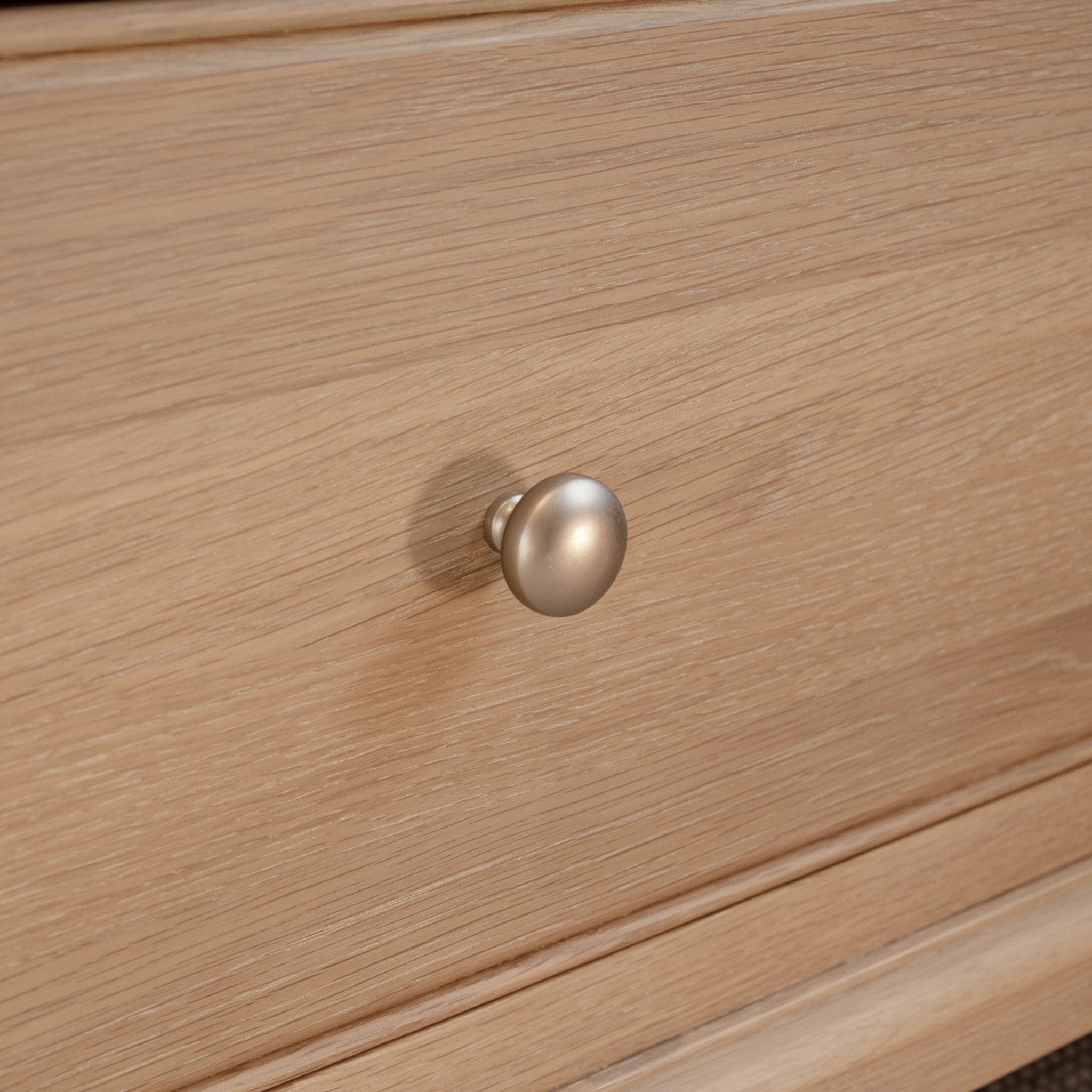 Close-up of a wooden drawer with a round, silver metal knob handle, featured in our Amberley Double Wardrobe in Light Oak.