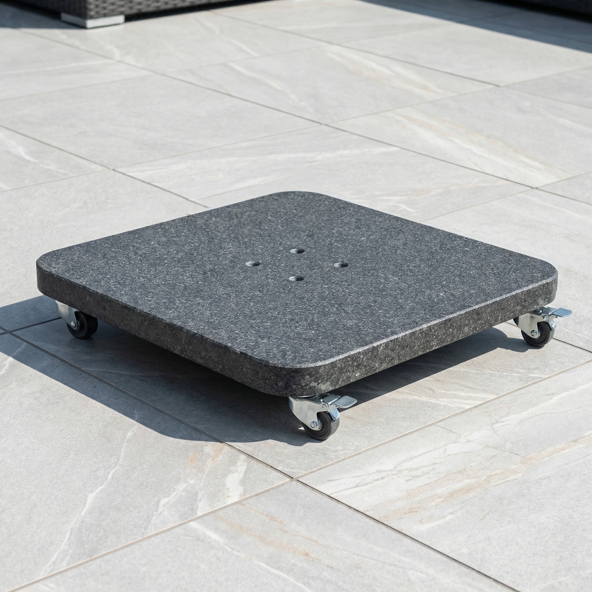 The Voyager T2 2.7m Square Cantilever Parasol in Taupe stands sturdily on a granite base with four caster wheels atop a tiled outdoor surface.