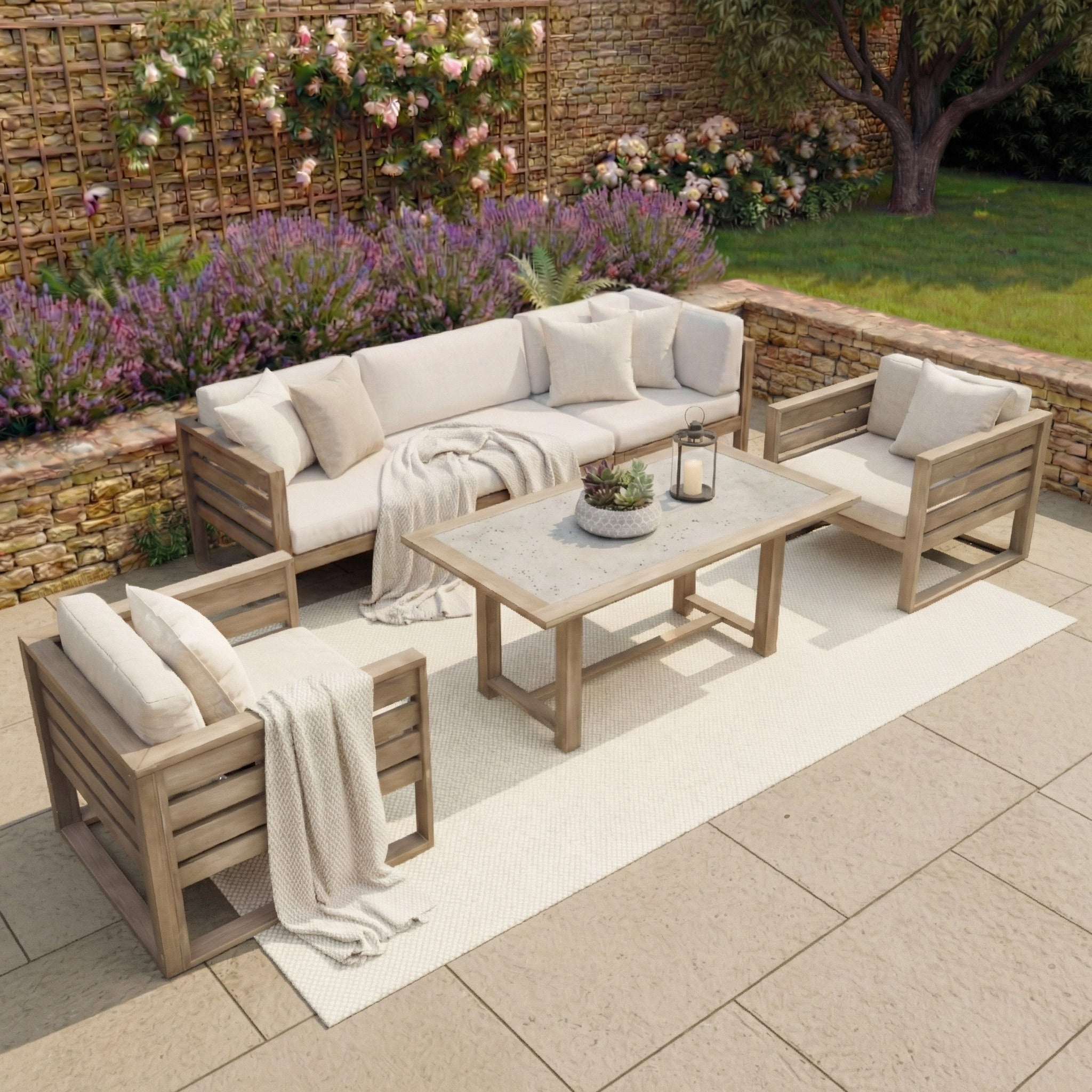 The Andora 3 Seat Sofa Set with 2 in 1 Table in Weathered Brown showcases a modular design with eucalyptus wood, beige cushions, and a rug, set amid flowers and lush greenery for a stylish outdoor patio retreat.
