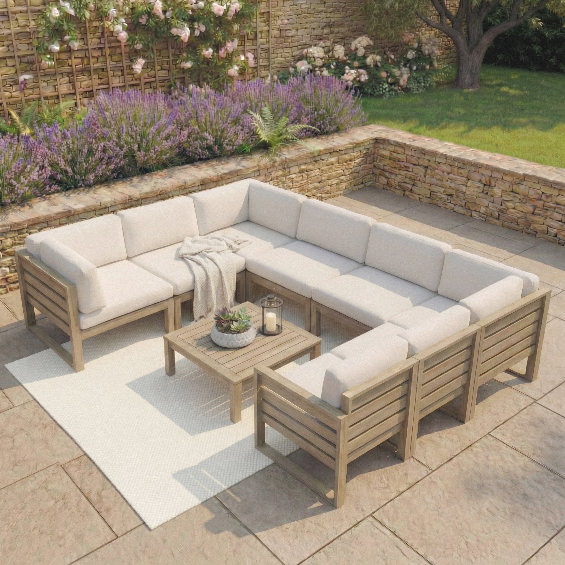 Outdoor patio with the Andora U-Shape Corner Sofa Set in weathered brown, coffee table/footstool, candles, blanket, and a white rug.