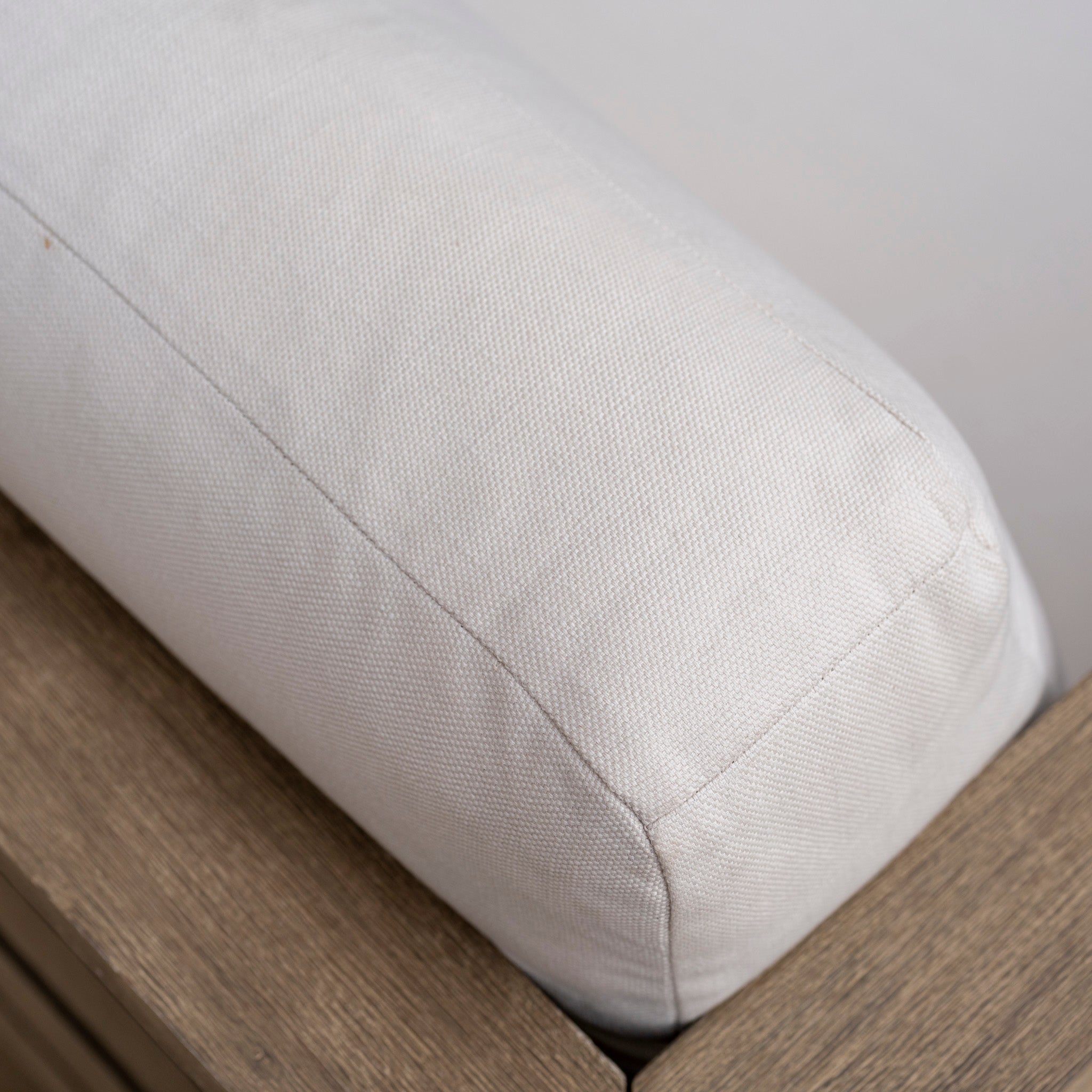 Close-up of a light-colored cushion on the wooden armrest of the Andora Large Corner Sofa Set with 2 in 1 Table in Weathered Brown, highlighting its modular outdoor design for comfort and versatility.