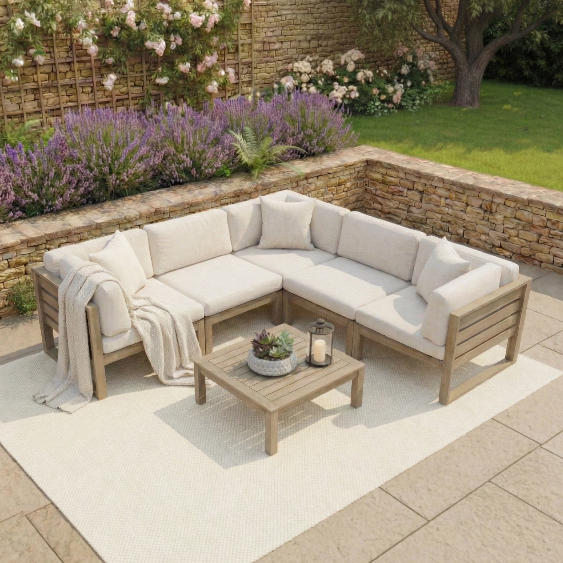 Outdoor patio featuring the Andora Corner Sofa Set with Coffee Table/Footstool in Weathered Brown, a white rug, and a lush garden—ideal for relaxing with stylish modular outdoor furniture.