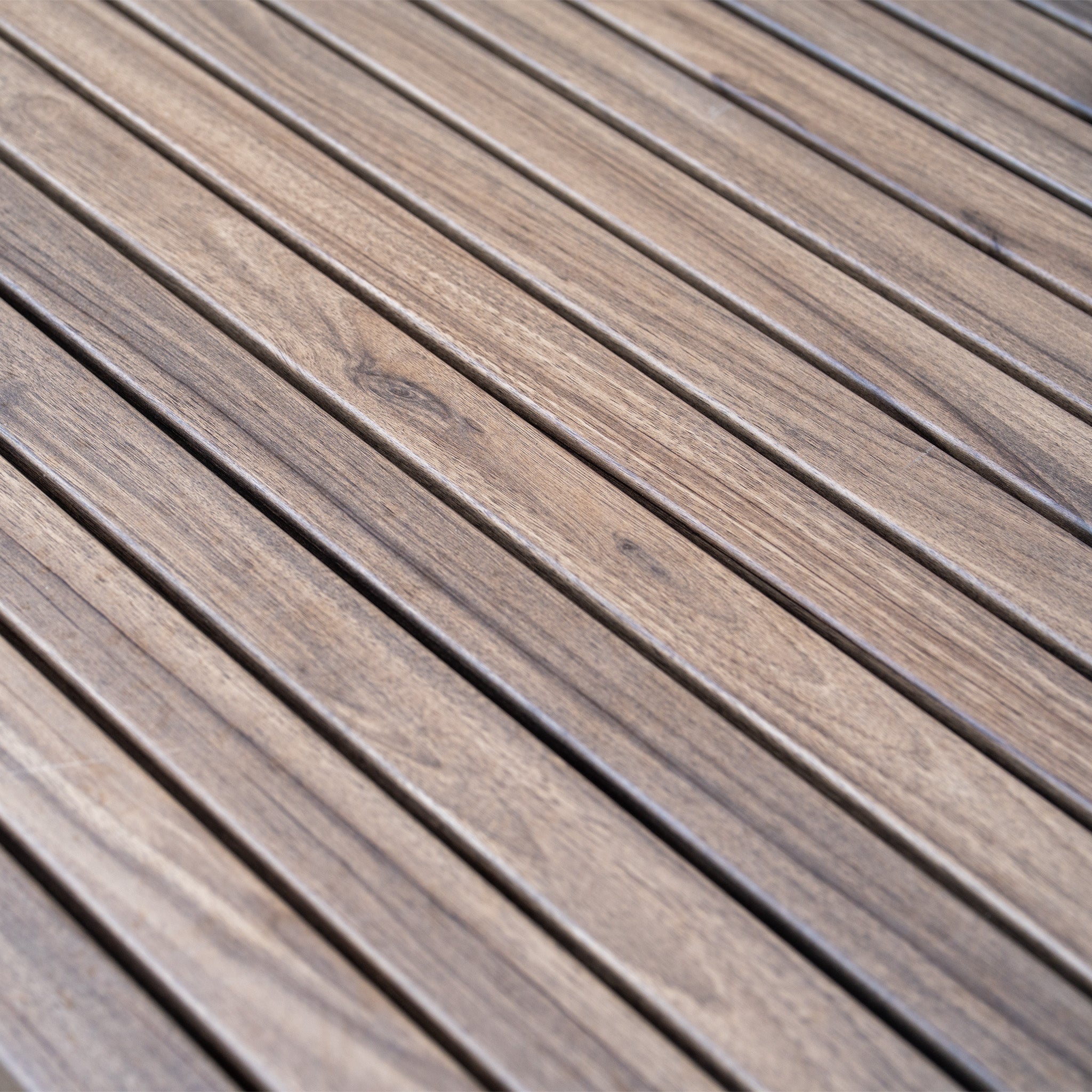 Close-up of smooth, light brown wooden planks arranged parallel, forming a flat surface—part of the elegant Ascot Corner Dining Set with Armchair in Forest Green, perfect for stylish garden furniture and outdoor dining.