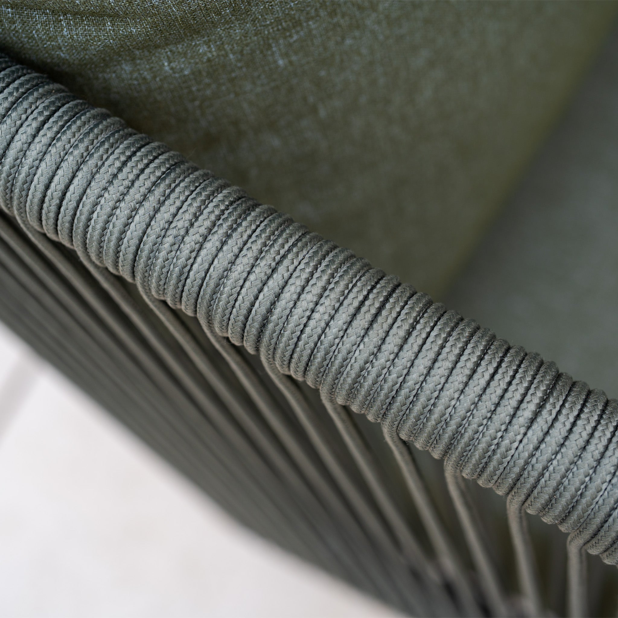 Close-up of a green rope-wrapped armrest with fabric upholstery from the Ascot Corner Dining Set with Armchair in Forest Green, ideal for adding modern style to your garden. Blurred background highlights its elegant outdoor dining appeal.