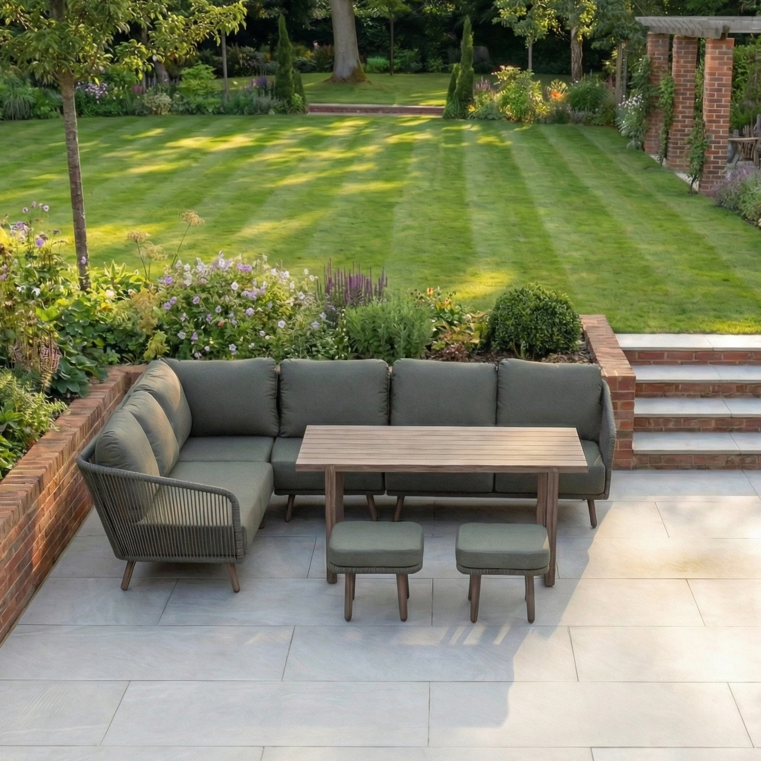 The Ascot Corner Dining Set in Forest Green, an L-shaped outdoor modular sofa and table, offers stylish and weather-resistant garden furniture for relaxing on your patio beside a manicured lawn and garden.