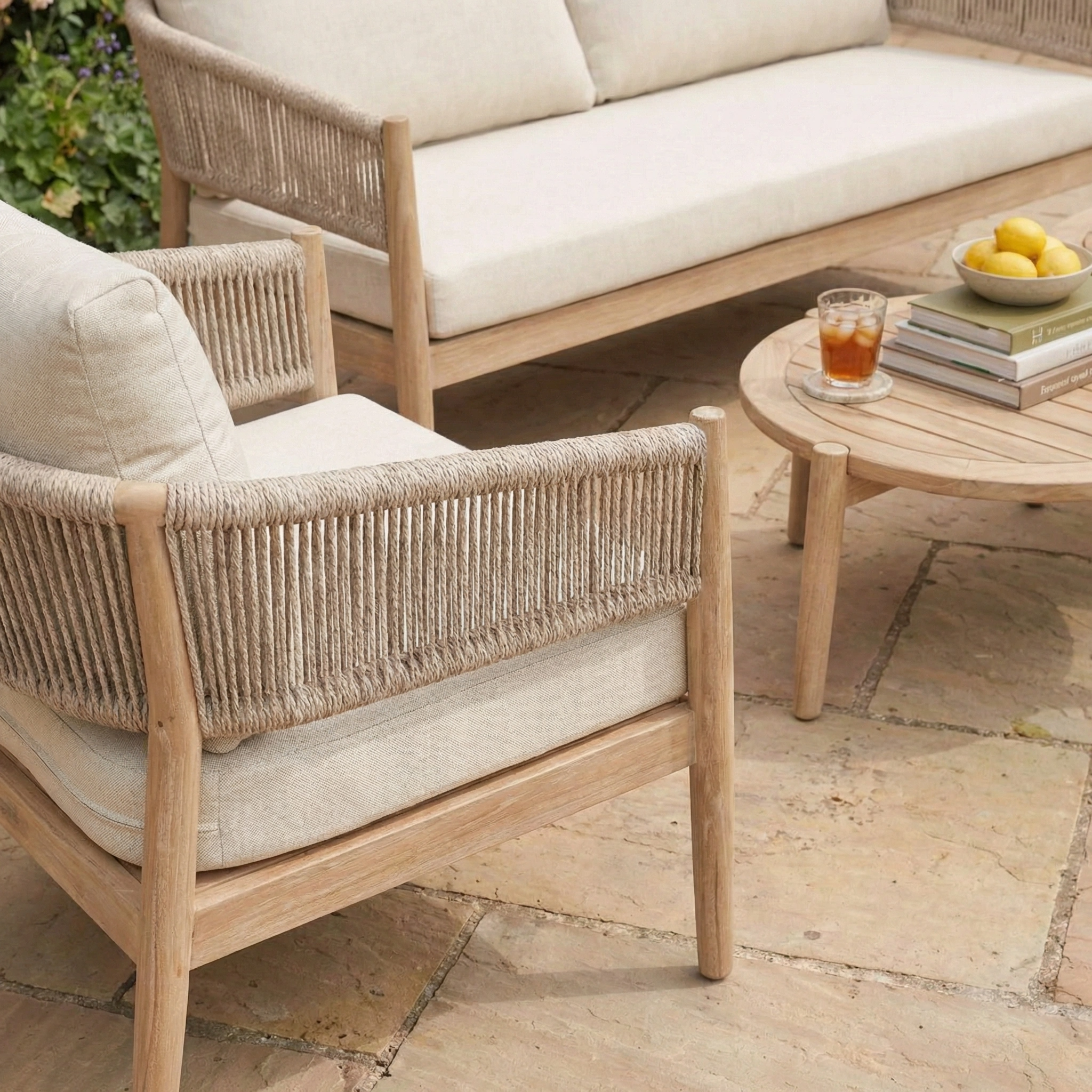 The Astoria 2 Seat Sofa Set in Ash Grey includes garden furniture with cream cushions and a round table—ideal for relaxing outdoors in style.
