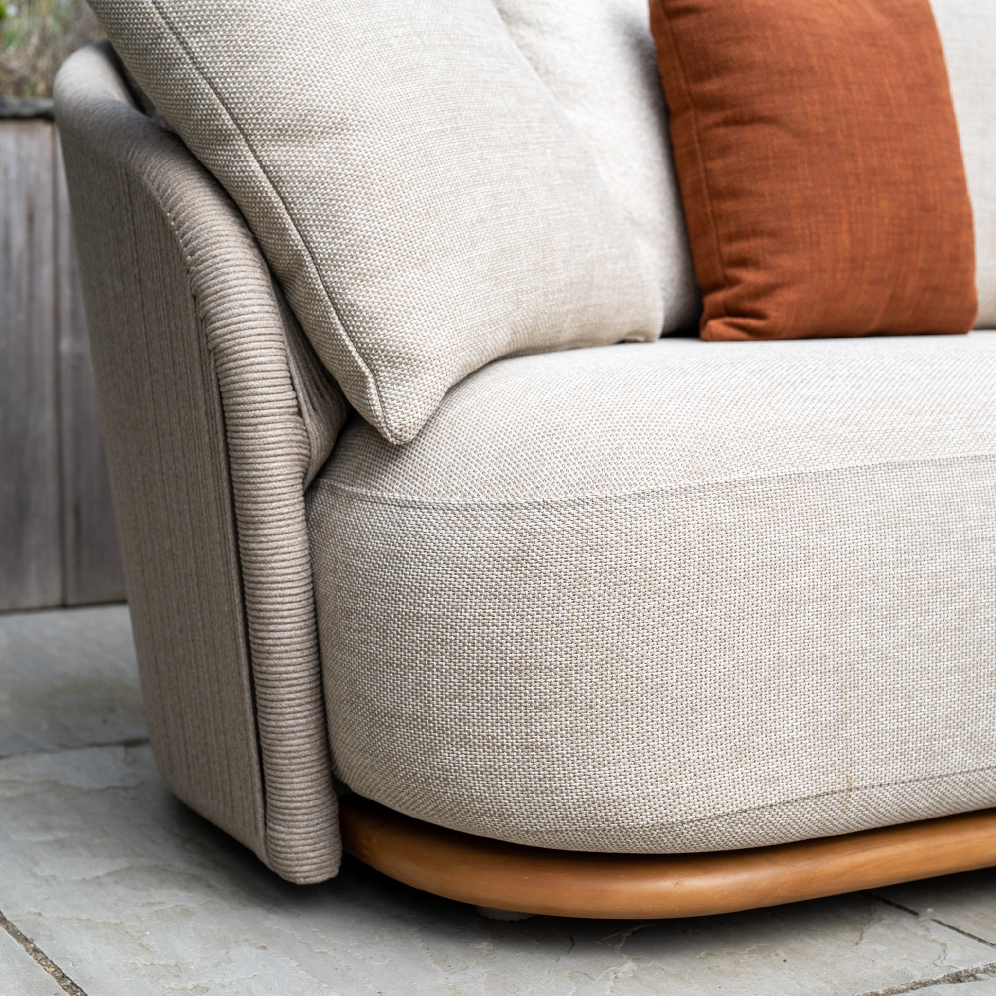 Close-up of the Avola Corner Sofa Set in Fawn, an outdoor sofa made with weather-resistant olefin and cream and rust pillows, displayed on a stone patio.