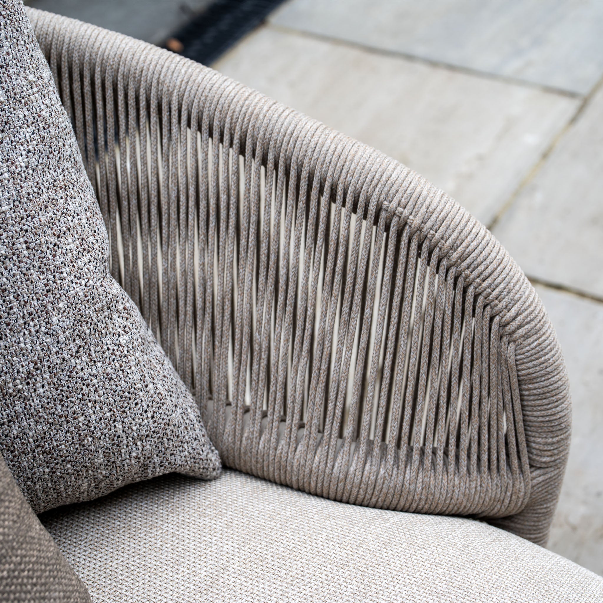 Close-up of the Avola Corner Sofa Set in Fawn, featuring beige weather-resistant olefin with woven rope details and a textured gray cushion.