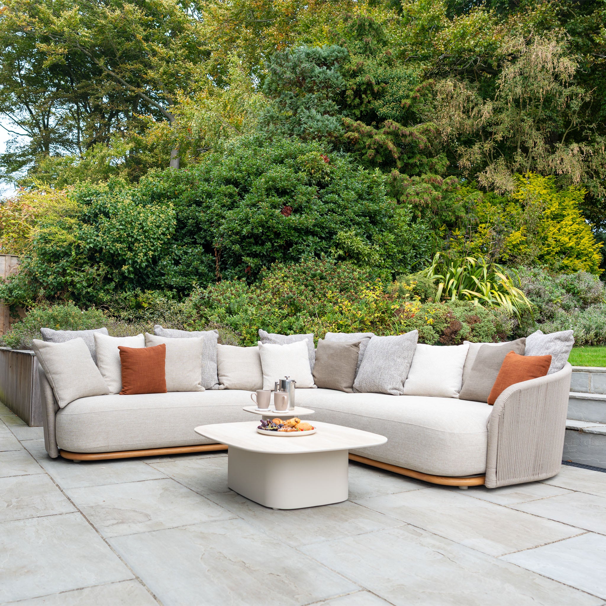 Create a stylish garden patio with the Avola Deluxe Corner Sofa Set in Fawn (Left Hand), featuring weather-resistant Olefin rope cushions, a curved outdoor sofa, and a tray-topped coffee table in premium teak and aluminium.