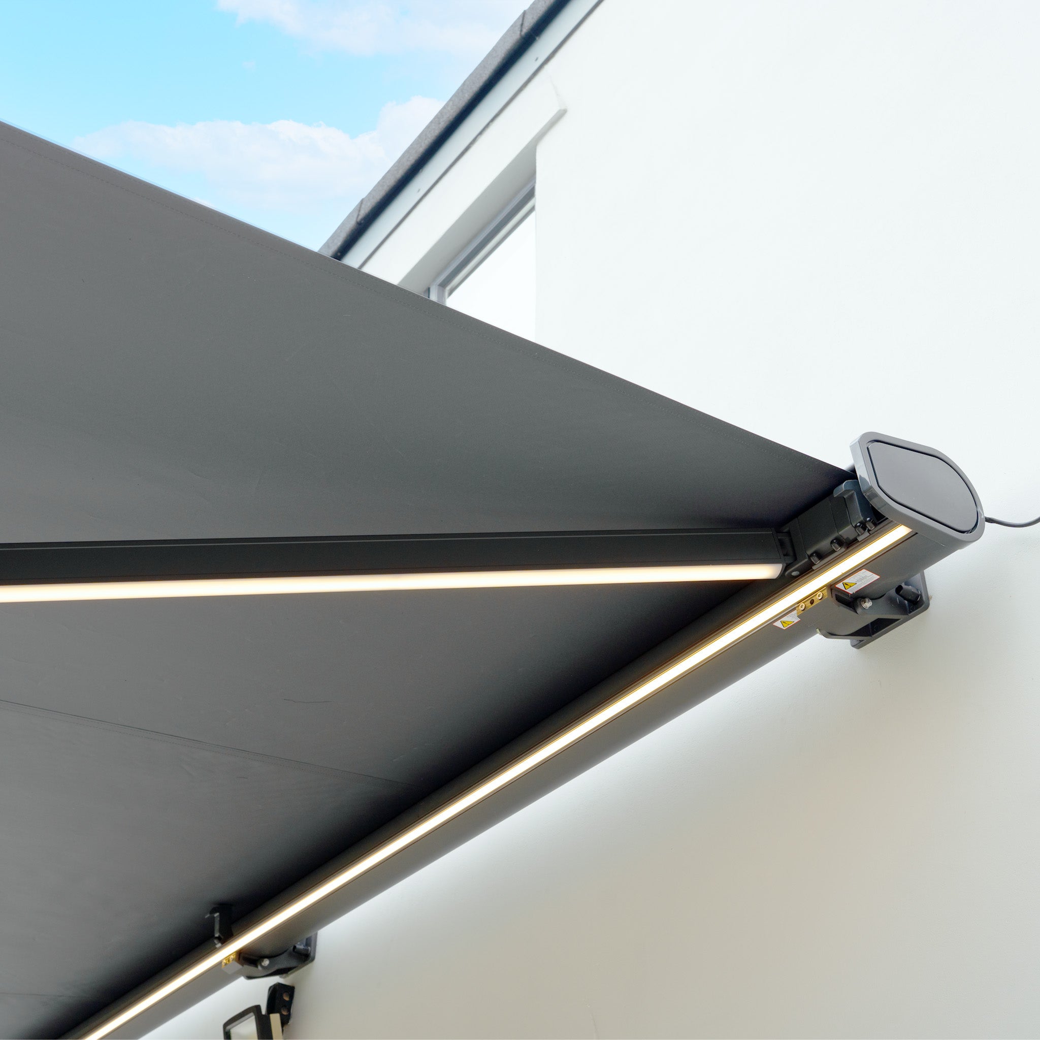 A 3m x 2m Electric Motorised Awning in Grey with built-in LED lights and waterproof acrylic fabric, mounted on a white exterior wall.