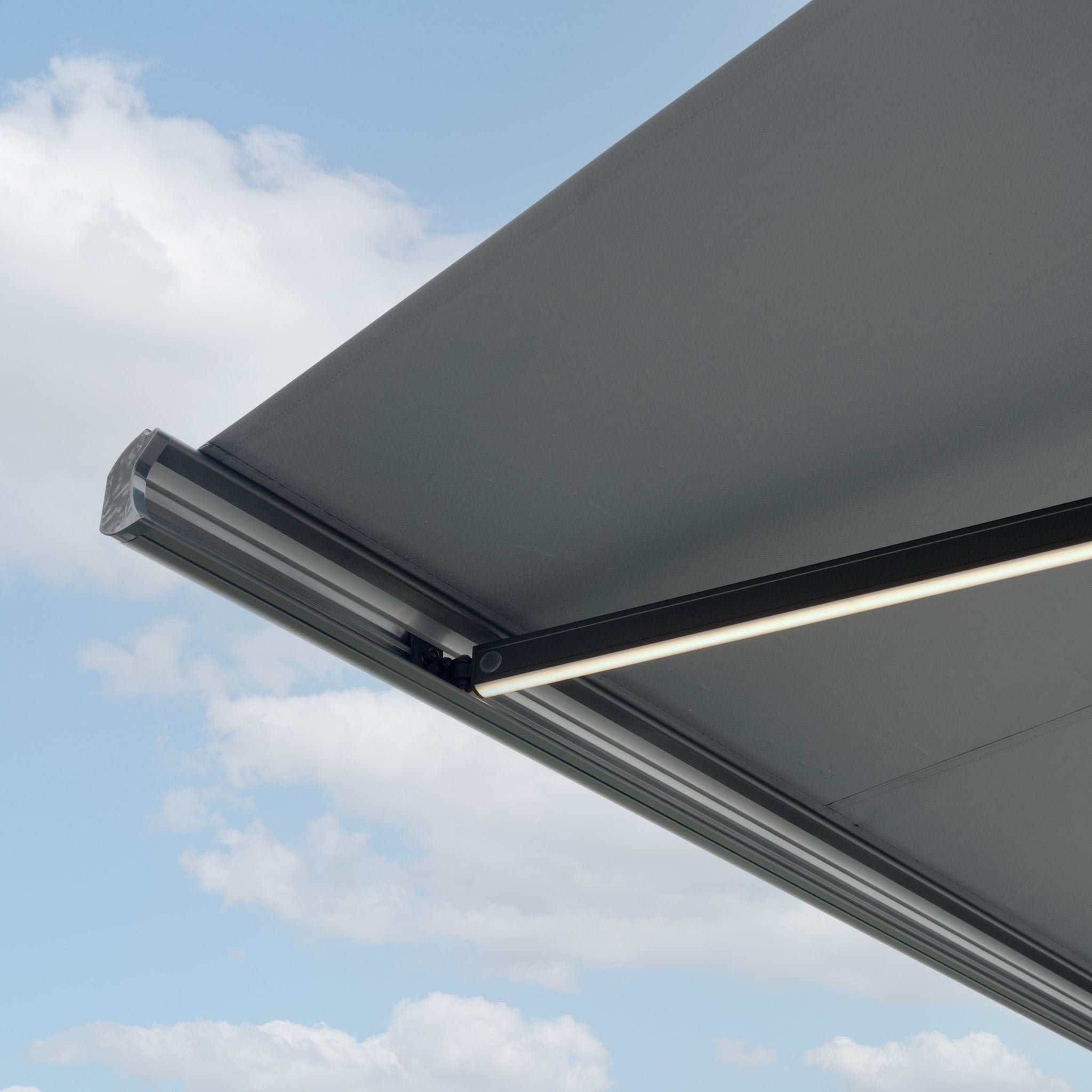 A close-up of the 3m x 2m Electric Motorised Awning in Grey with waterproof acrylic fabric extended under a cloudy sky.