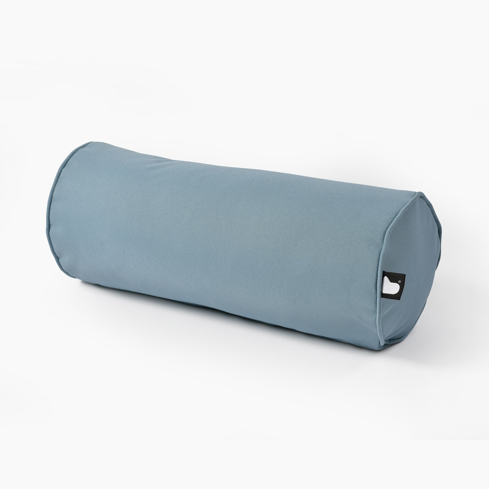 The Outdoor B-Bolster Cushion in Sea Blue is a cylindrical pillow featuring a small black tag on its side, designed to enhance your lounging experience.