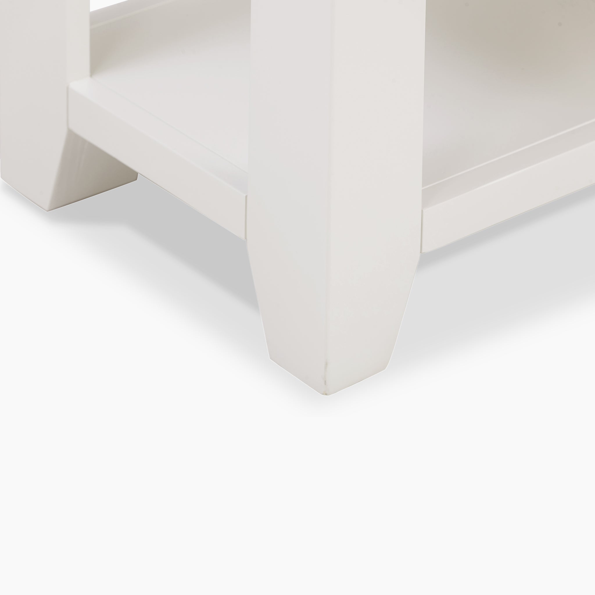 Close-up of the smooth-finished leg of a Burford 2 Drawers Console Table in Warm White, highlighting its rectangular base against a light gray background.