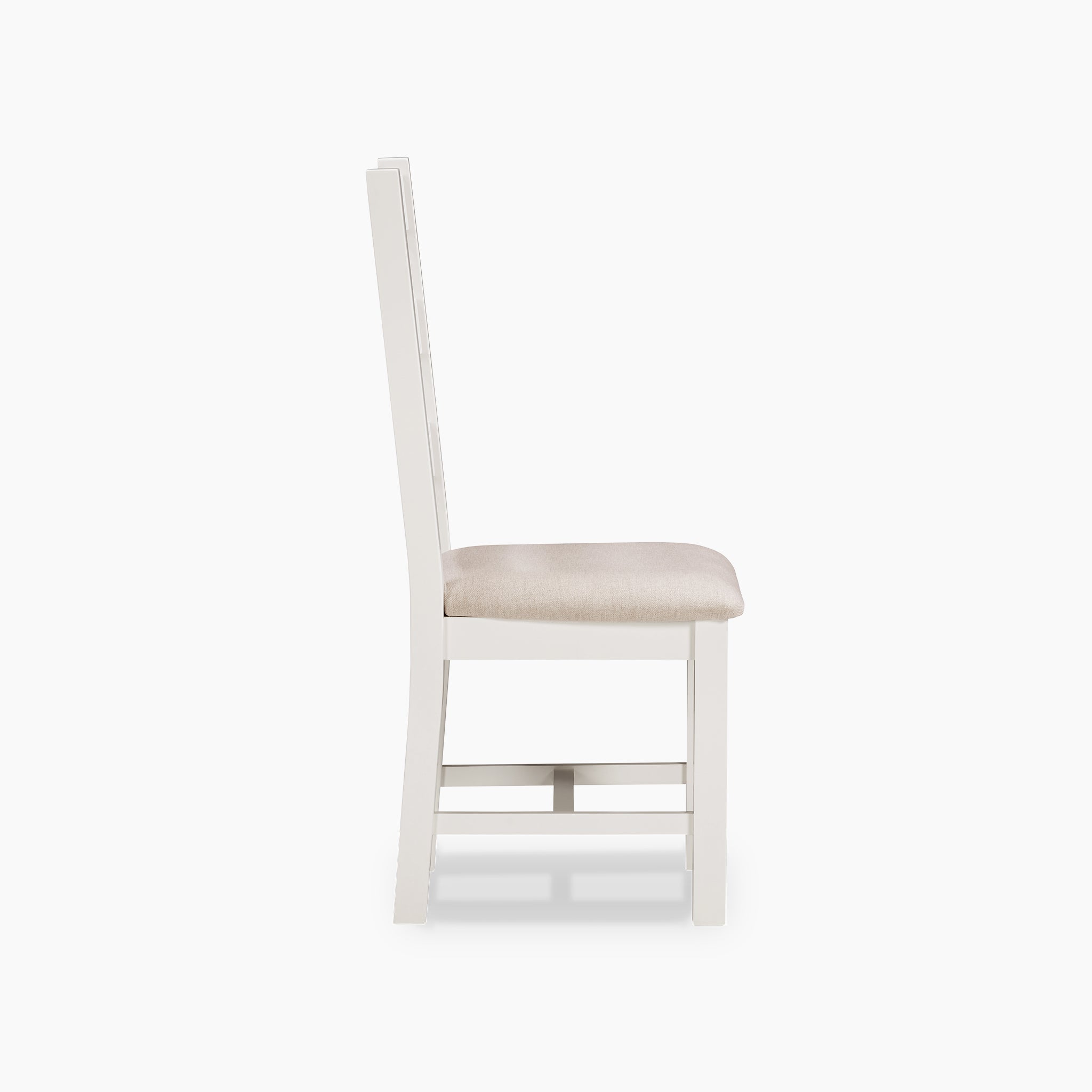 Side view of a white wooden chair with a beige cushioned seat on a white background, highlighting the sophistication of the Burford 8 Seat Extending Dining Set in Warm White.