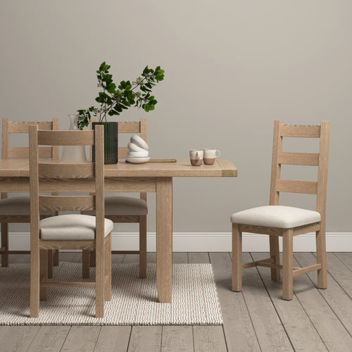 A burford extending dining set in natural oak with a rug underneath it