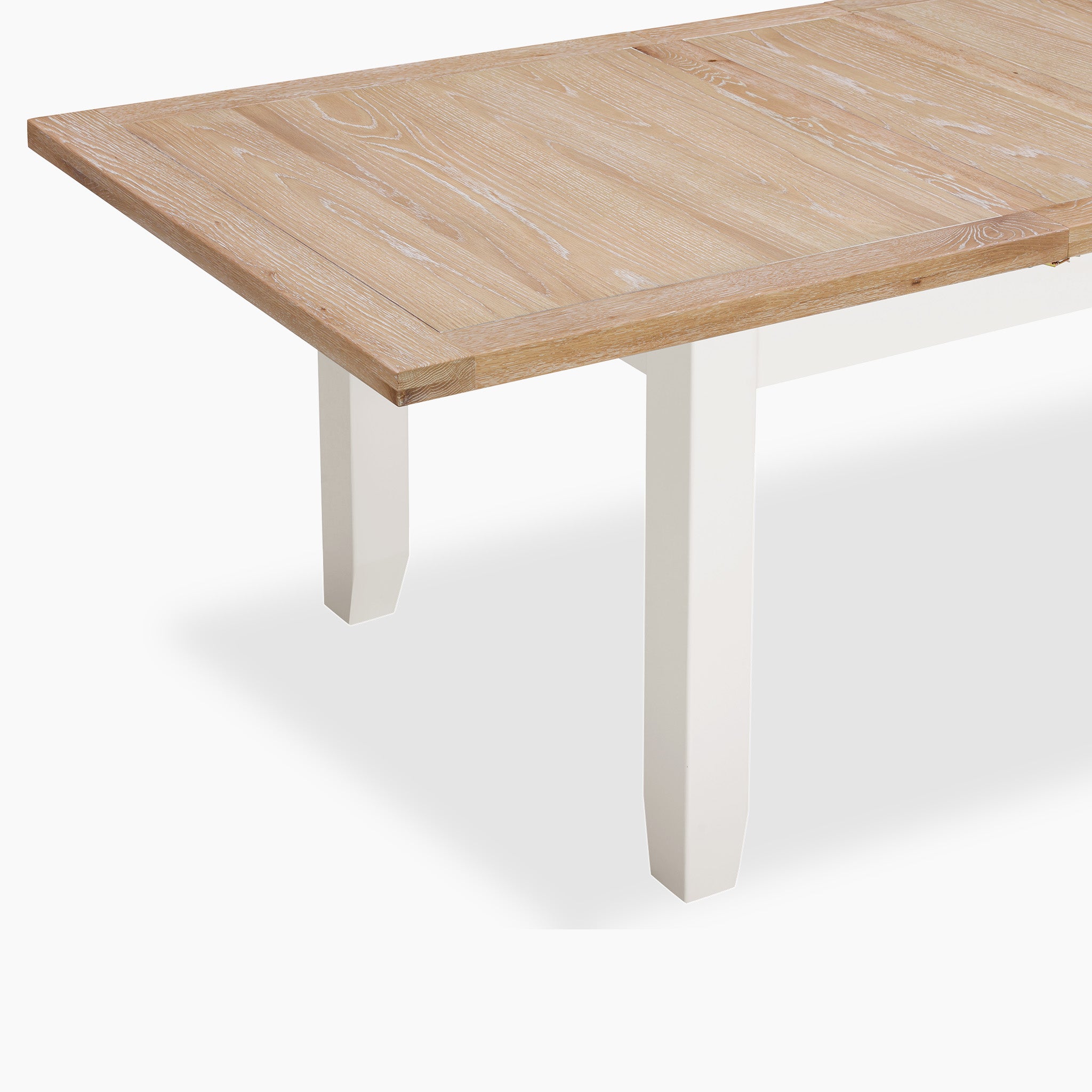 The Burford 8 Seat Extending Dining Set with Spindleback Dining Chair in Warm White features a rectangular solid oak table with white legs, shown angled on a white background—ideal for spacious dining.