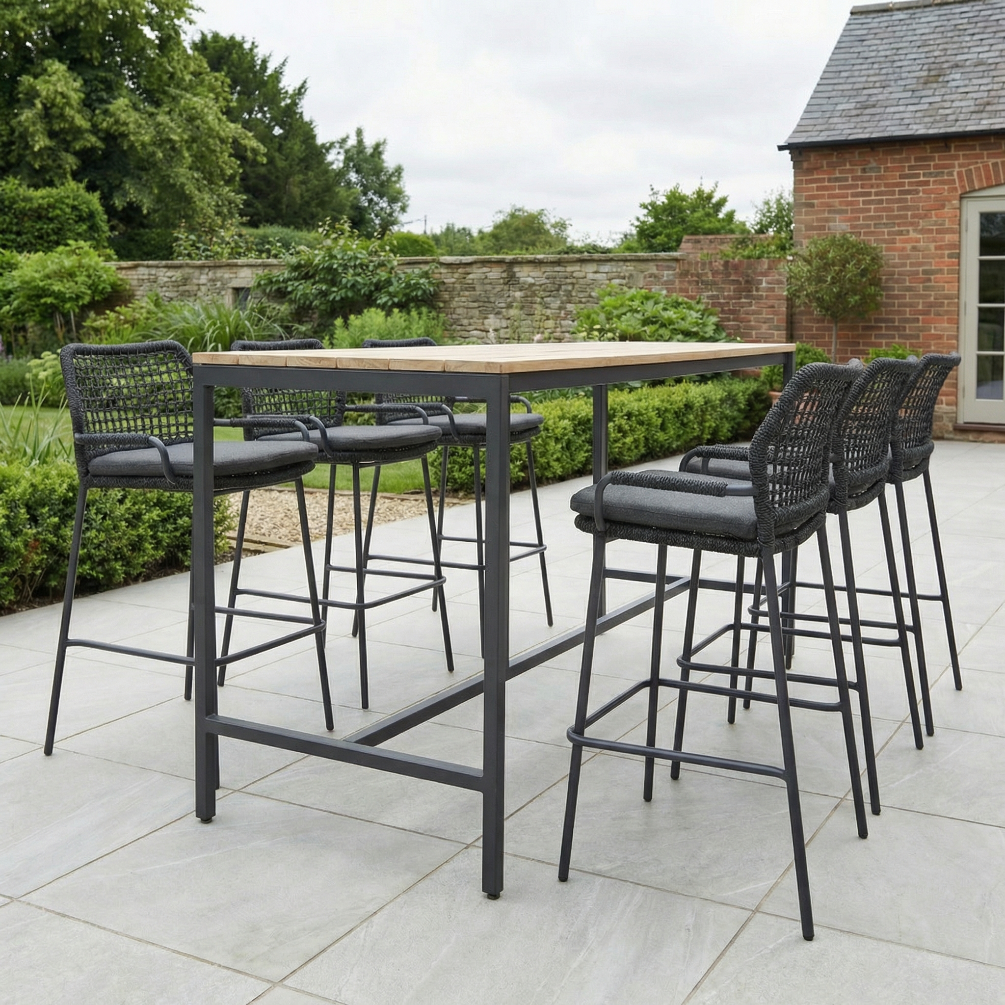 The Barista 6 Seat Bar Set with Teak Table in Anthracite features six black woven bar chairs with hairpin legs, perfect for stylish outdoor gatherings on your patio or in your garden.