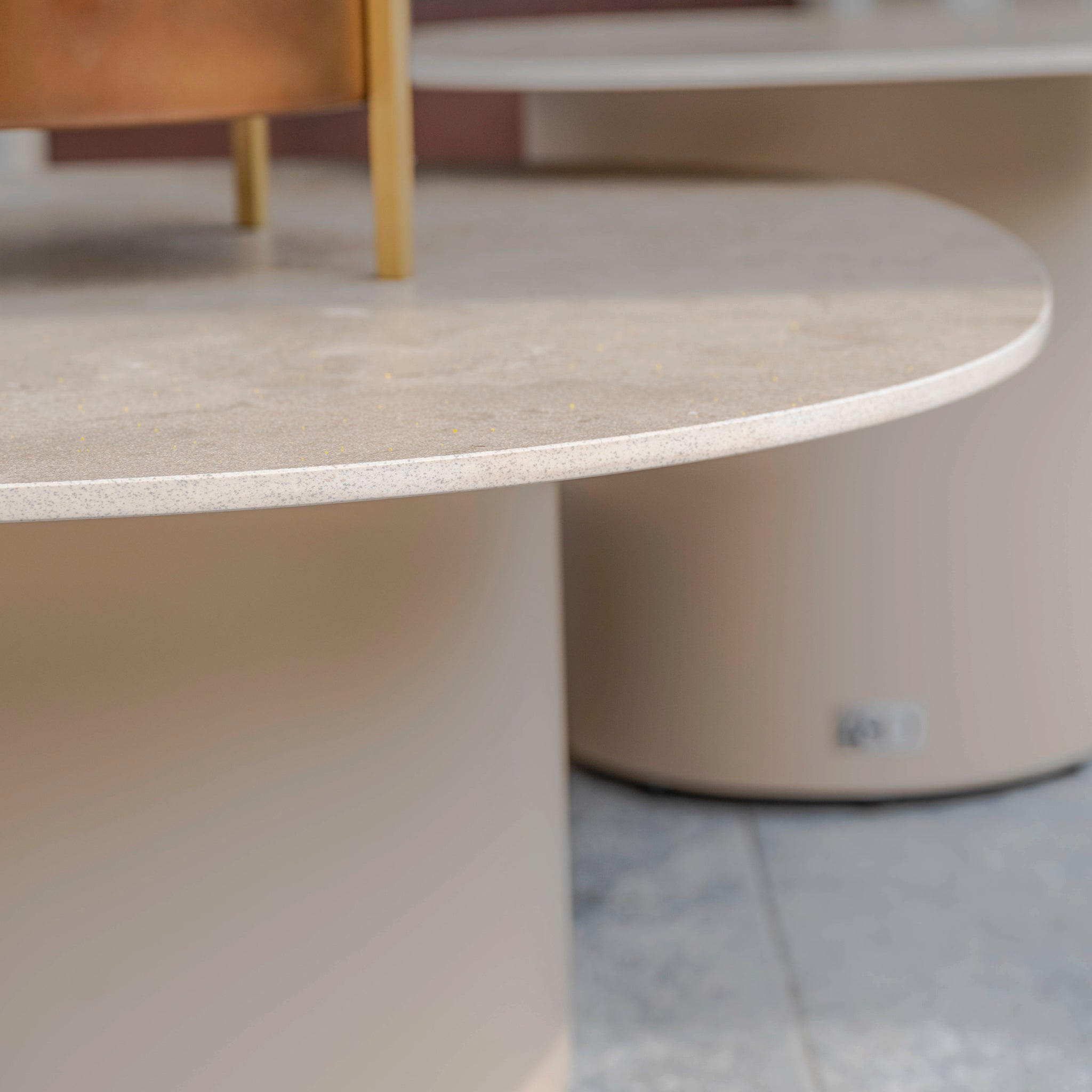 Close-up of a light-colored, round table with speckled texture and beige cylindrical base, perfectly complementing the Madeira 3 Seat Sofa Set in Striped Latte in this elegant garden furniture arrangement.
