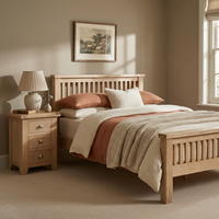 Cozy bedroom featuring the Burford 4ft 6" High-End Double Bed Frame in Natural Oak, a matching nightstand, warm bedding, and a lamp beside the window.